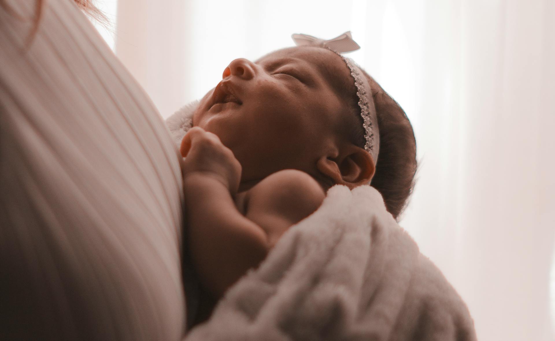 A mother carrying an adorable baby girl | Source: Pexels
