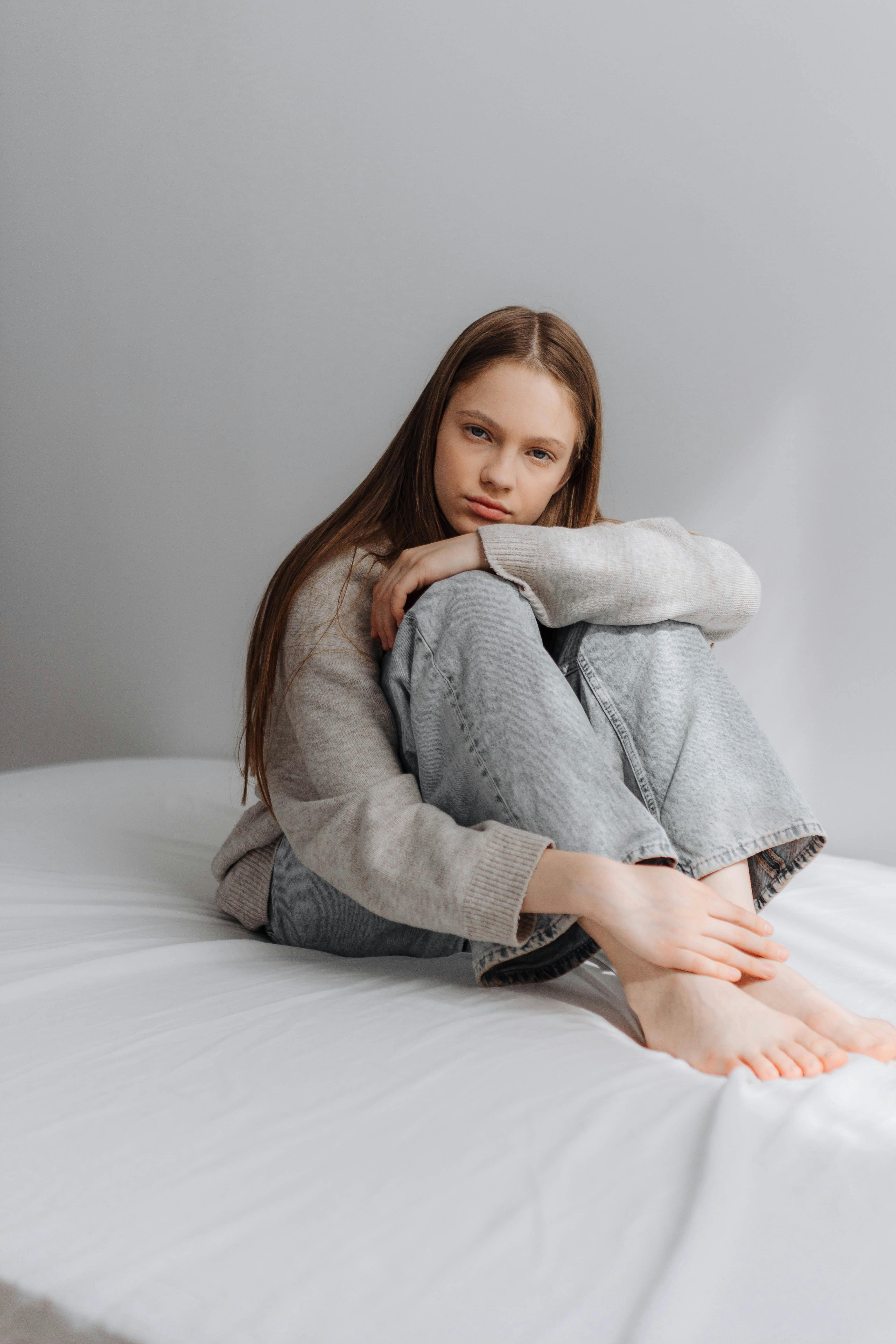 A young girl sitting on a bed | Source: Pexels