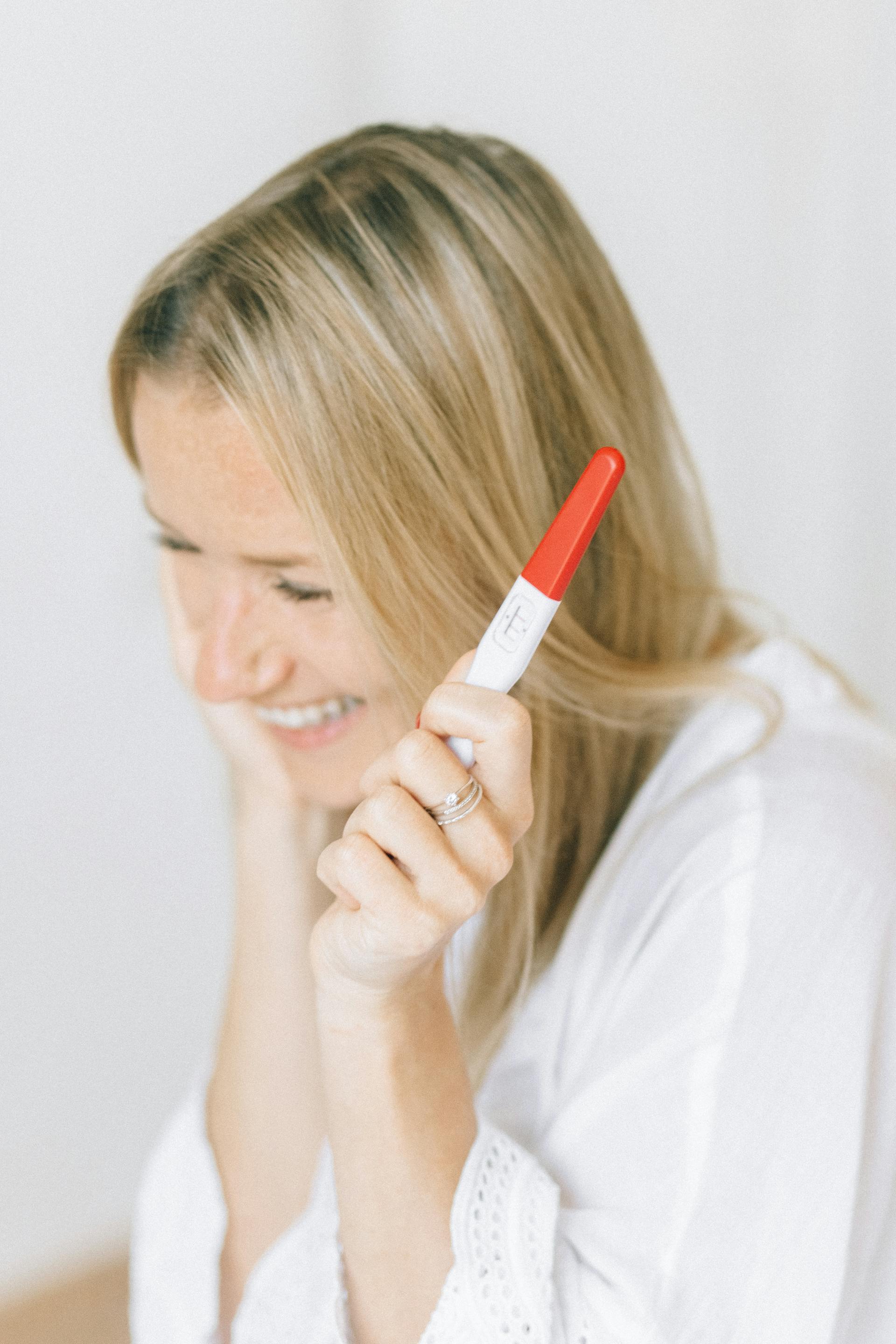 A happy woman holding a pregnancy test | Source: Pexels