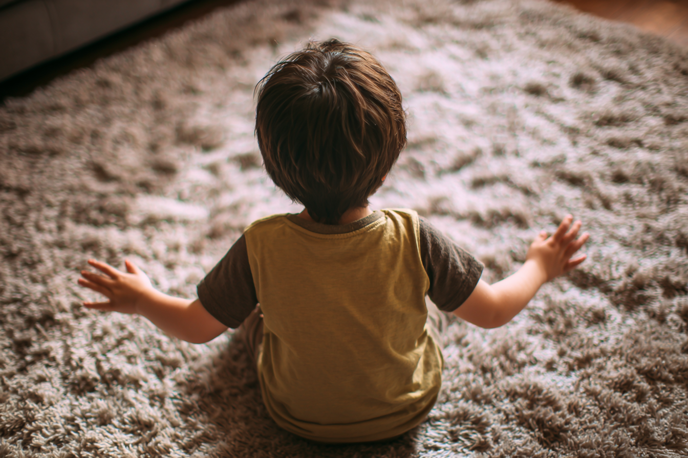 A child sitting on a carpet joyfully flapping his hands | Source: Midjourney