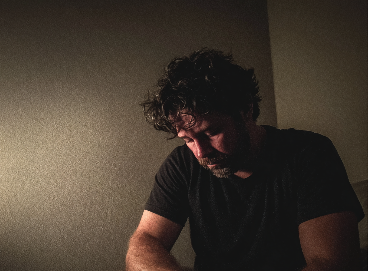 An upset man sitting on the edge of a bed | Source: Midjourney