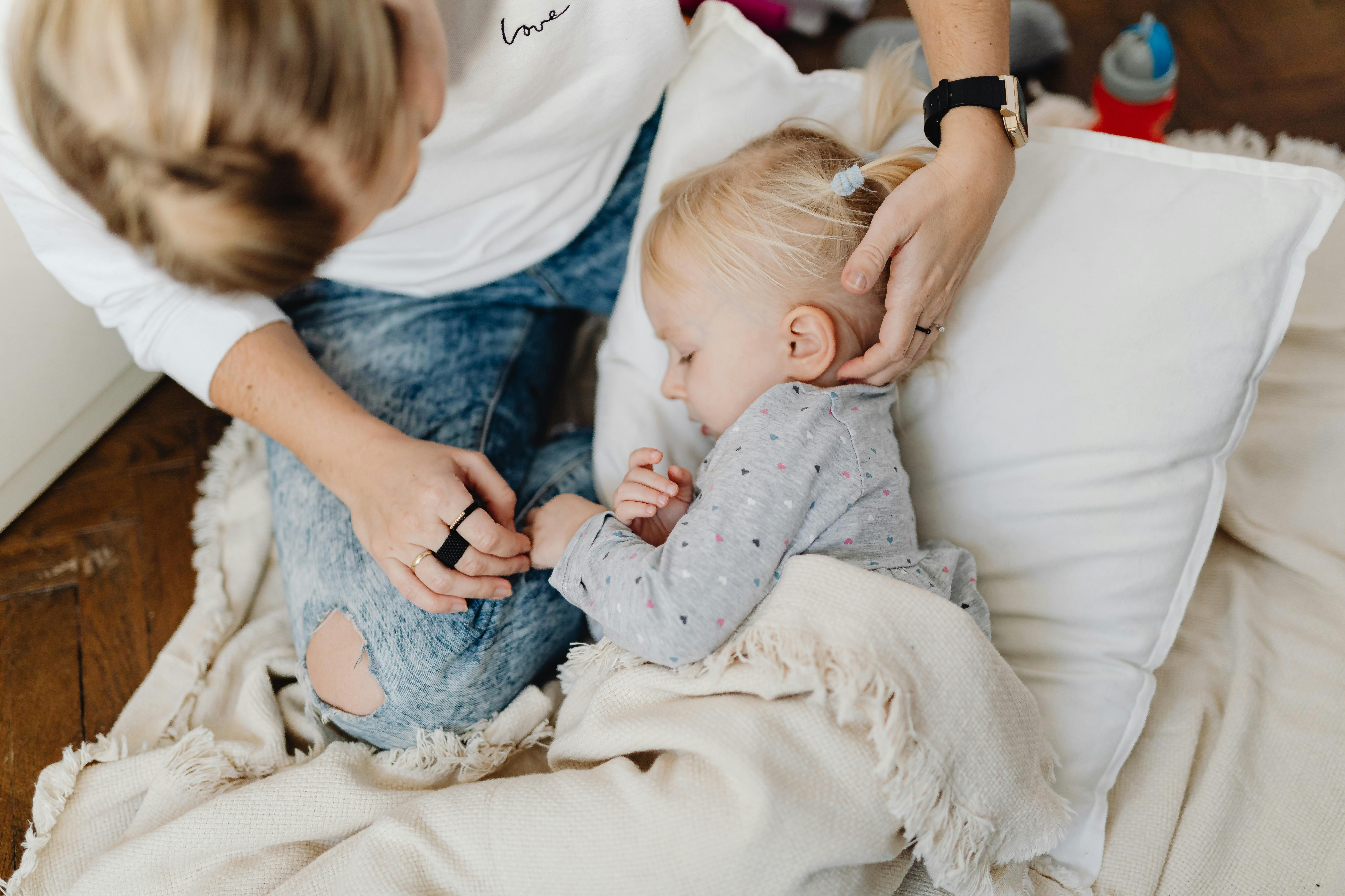 Woman tucking her daughter in bed | Source: Pexels