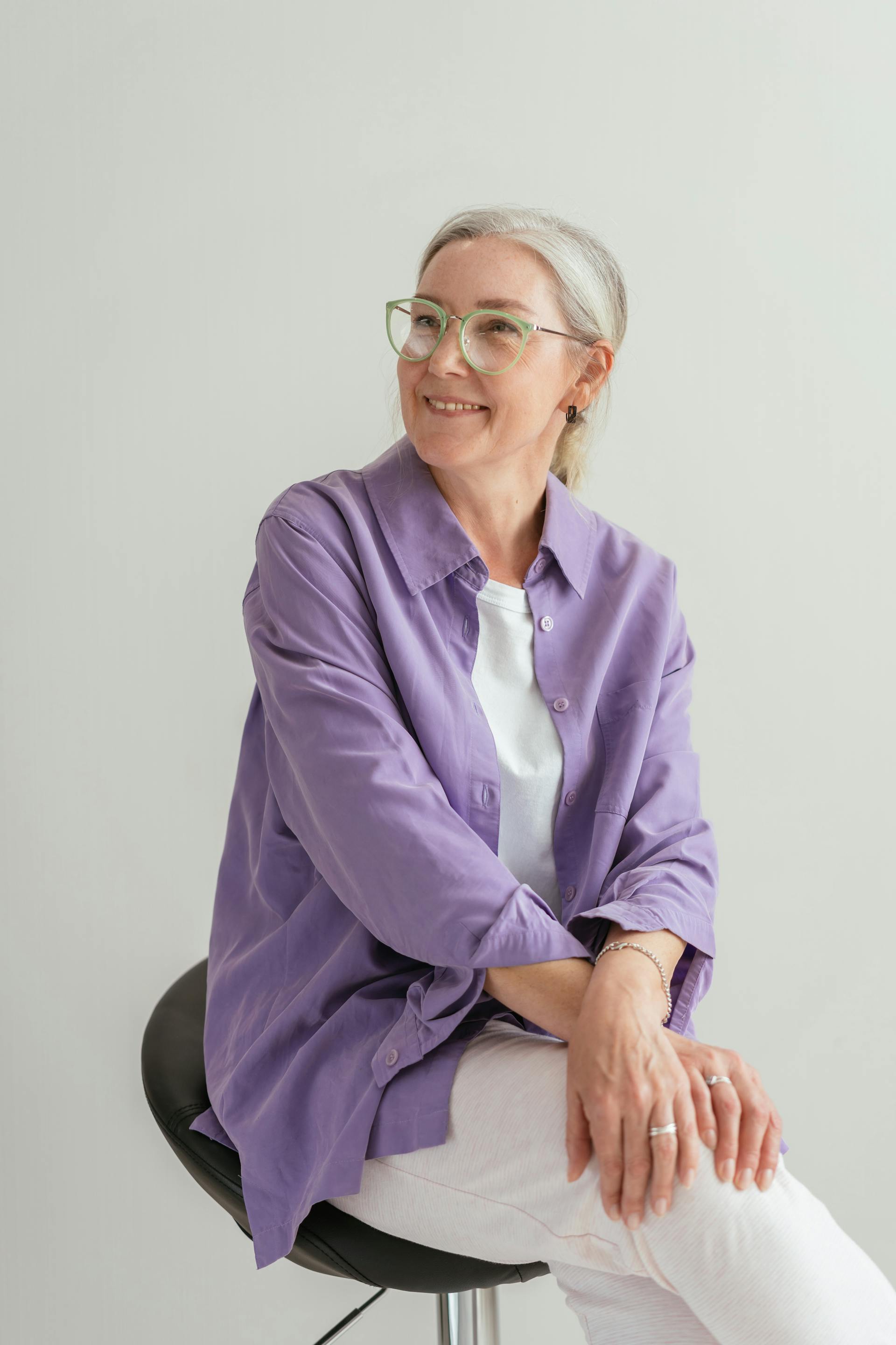 A smiling woman sitting on a black chair | Source: Pexels
