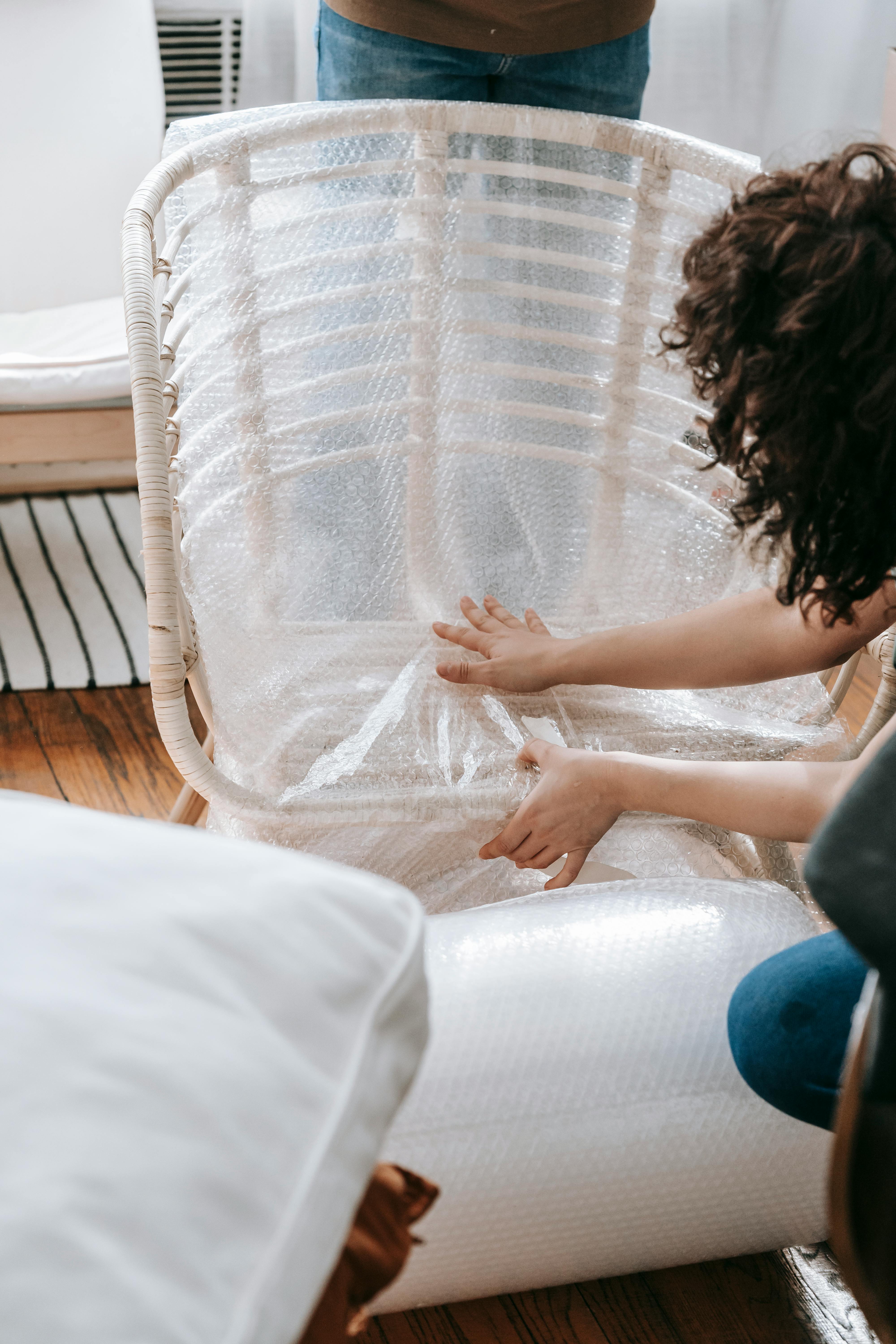 A woman wrapping a chair in bubble wrap | Source: Pexels