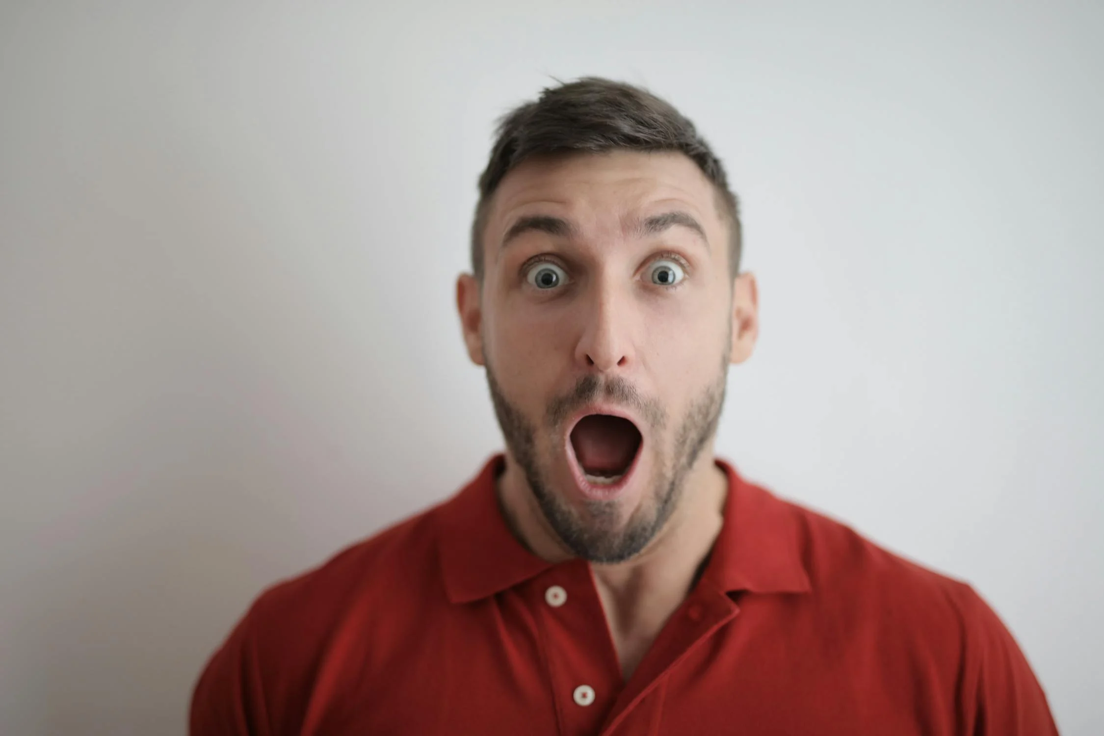 A shocked man in a red polo | Source: Pexels