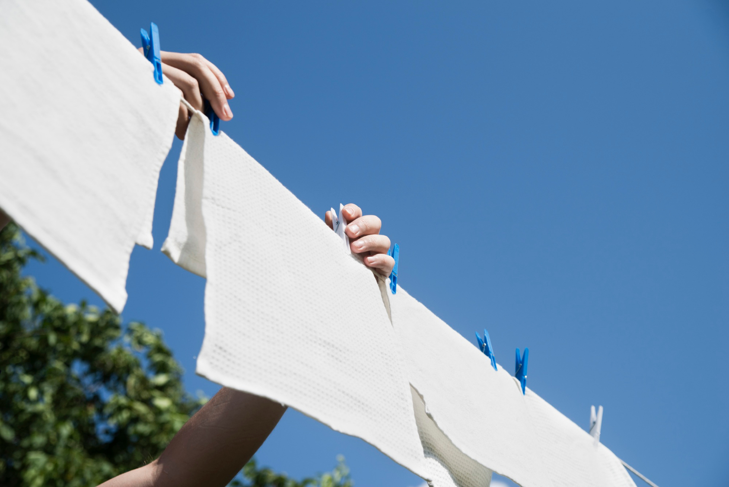 A woman clipping laundry to a clothesline | Source: Freepik