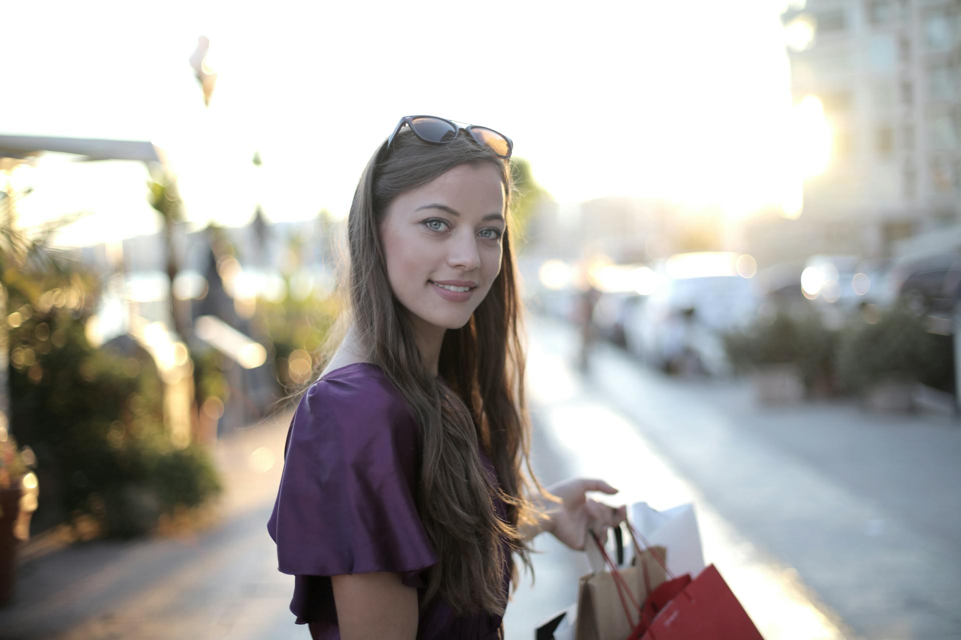 A woman holding shopping bags and smiling awkwardly at someone | Source: Pexels