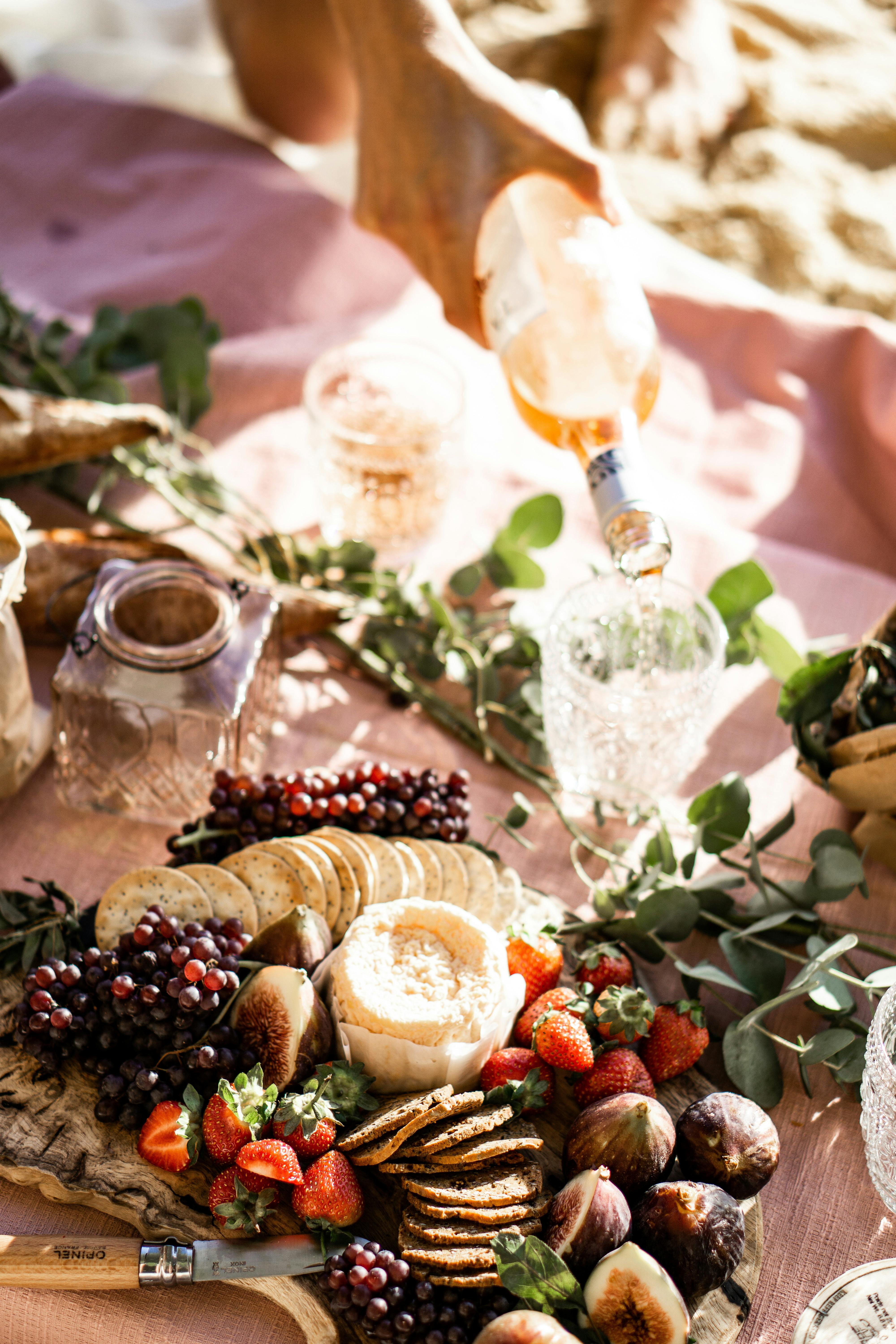 A woman pouring wine while sitting with a snack board | Source: Pexels