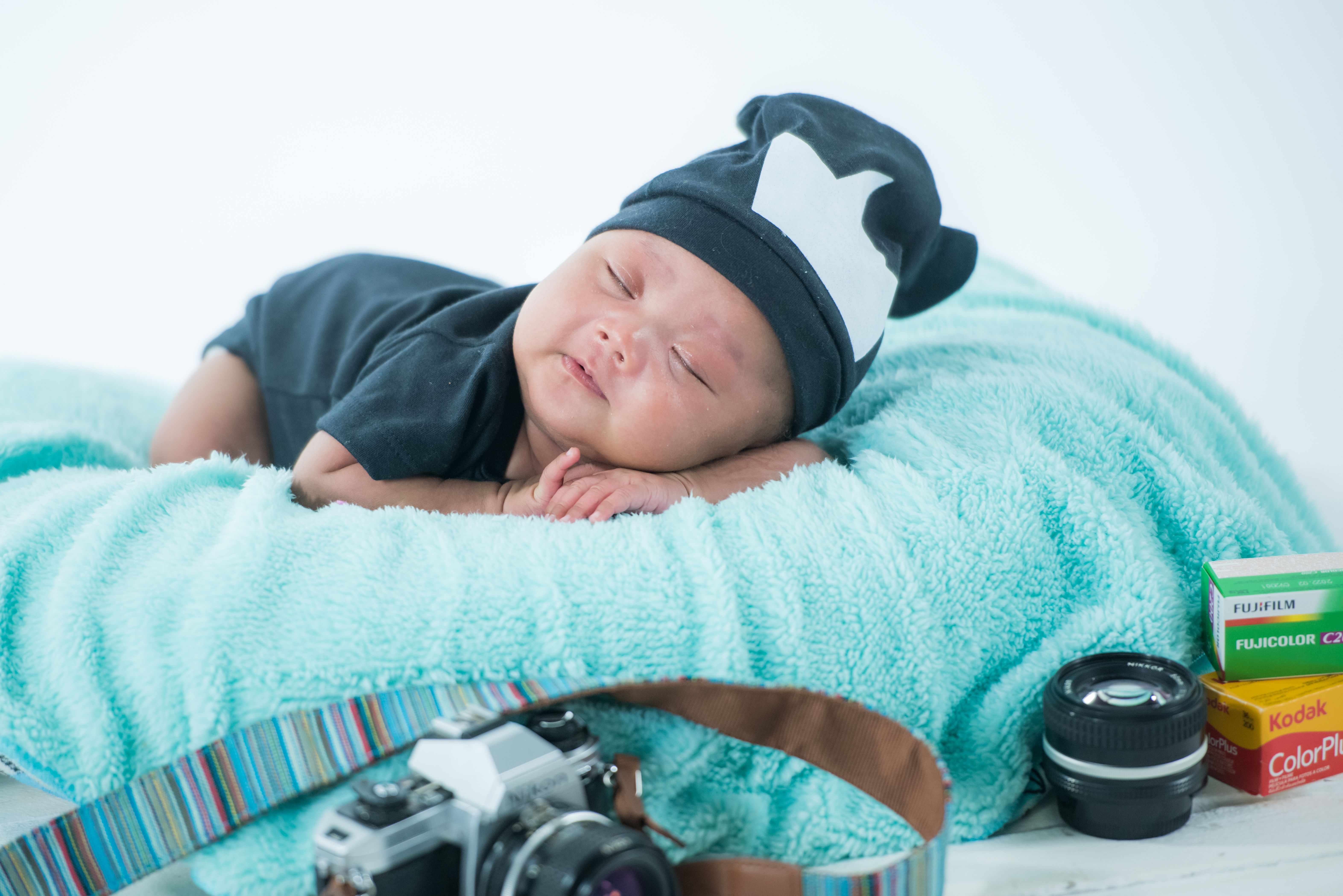 A cute sleeping baby with a camera on a cozy blanket in a studio setting | Source: Pexels