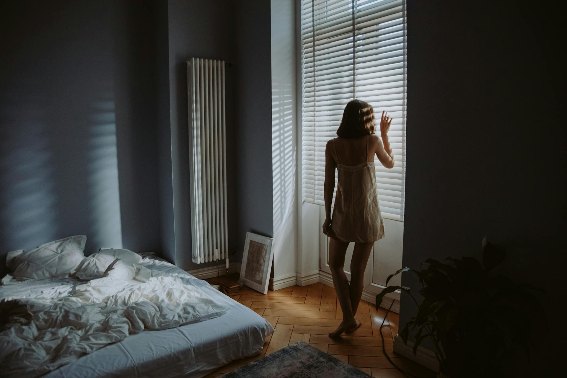 A woman standing near the window shutters of her bedroom | Source: Pexels