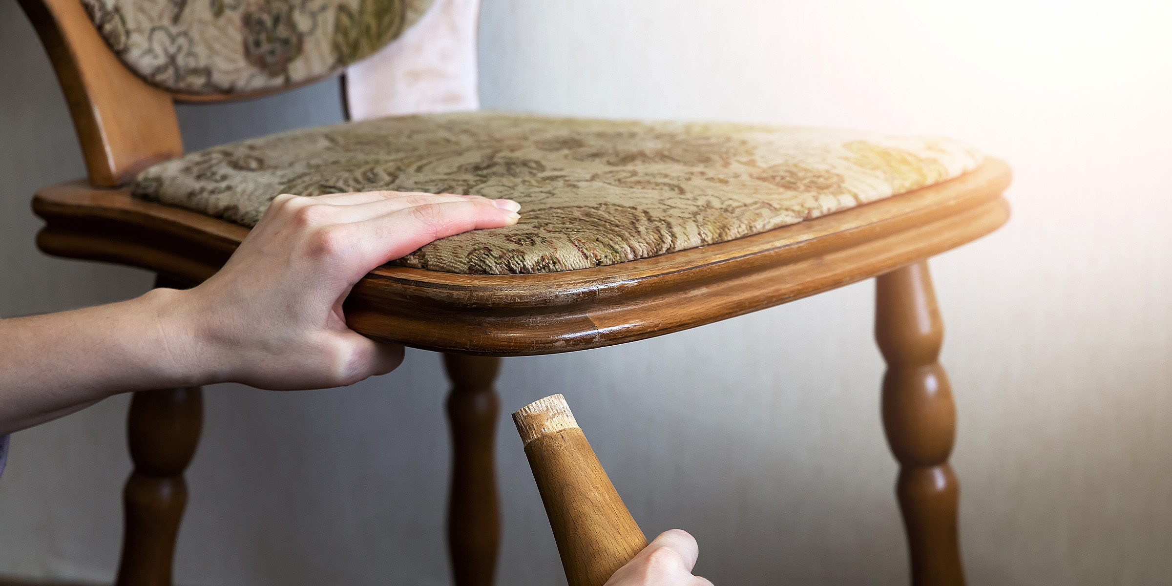 A woman holding the leg of a broken chair | Source: Shutterstock