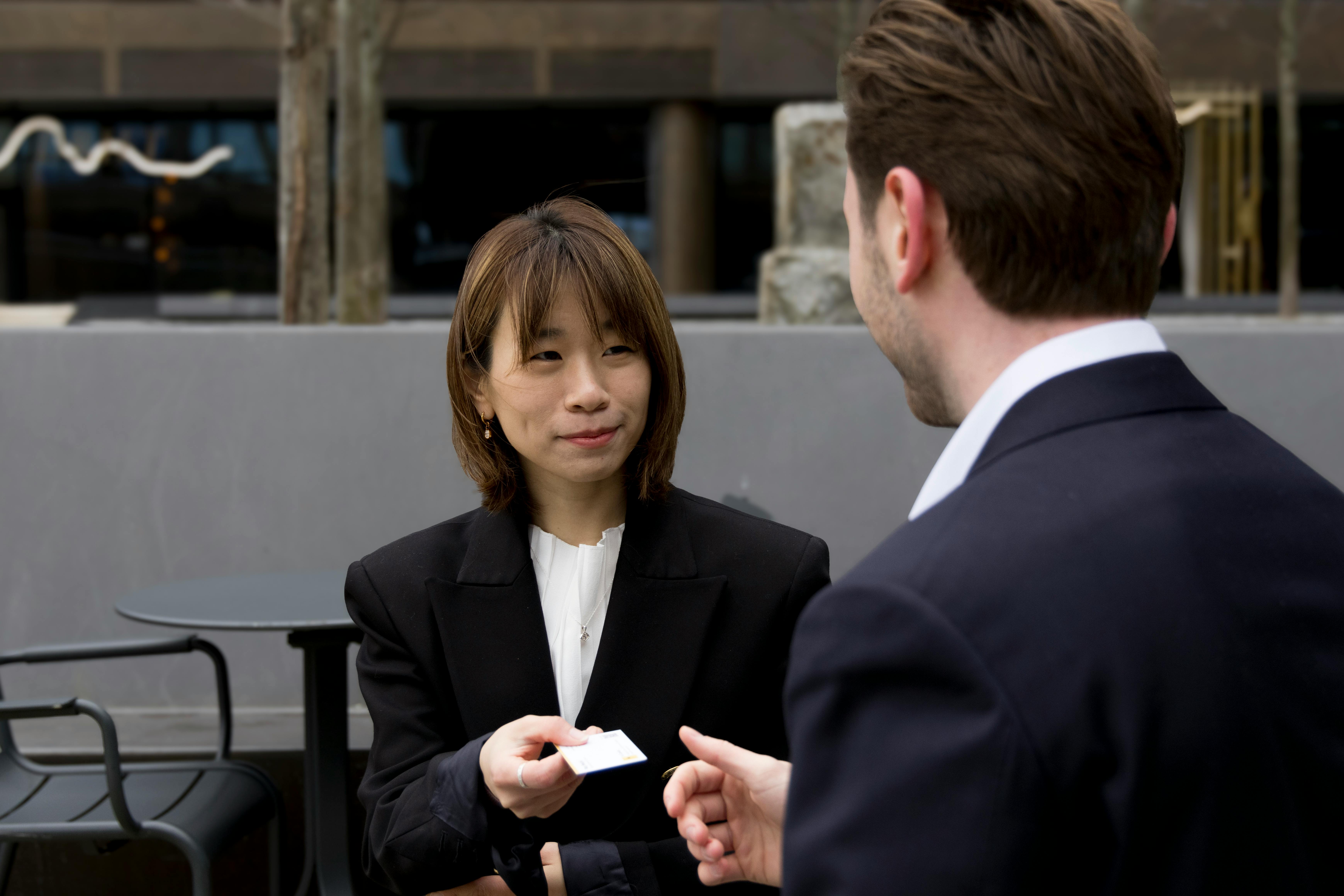 A woman handing over her business card to a man | Source: Pexels