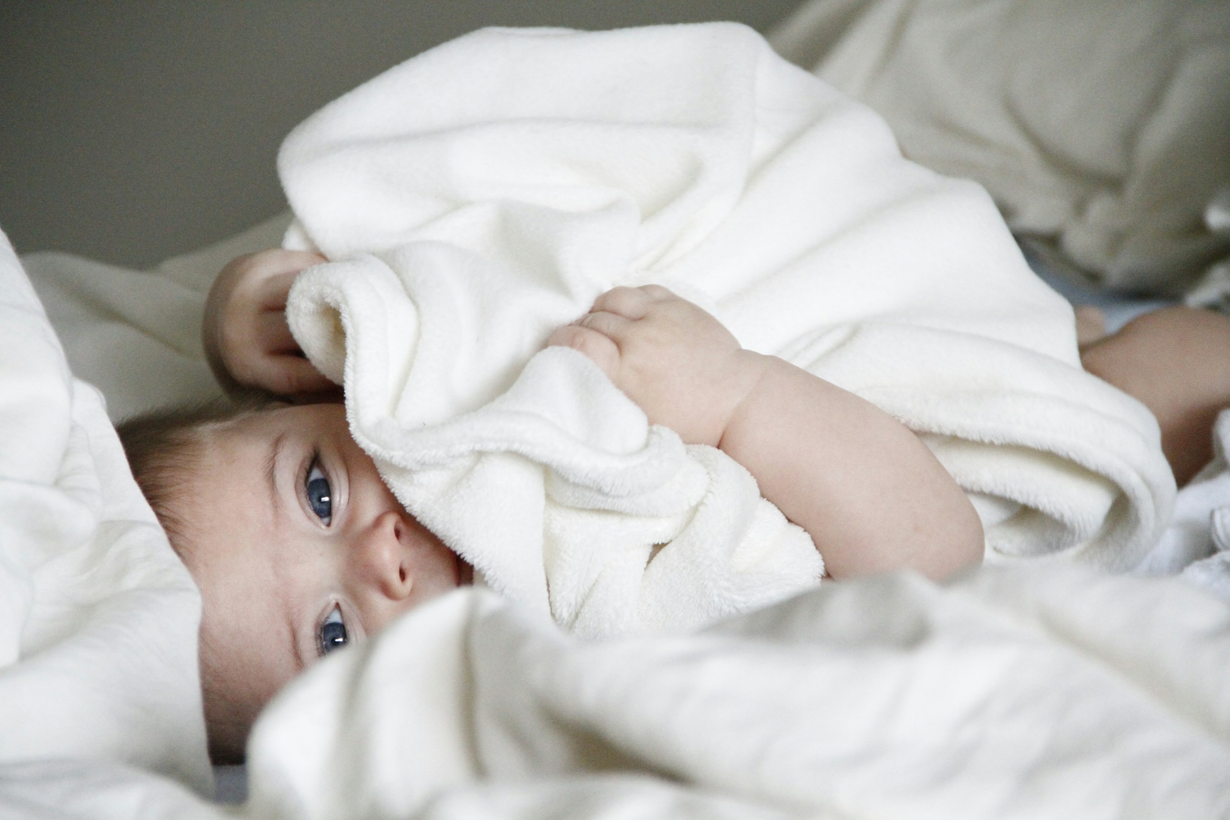 A baby covered in a cozy white blanket | Source: Unsplash