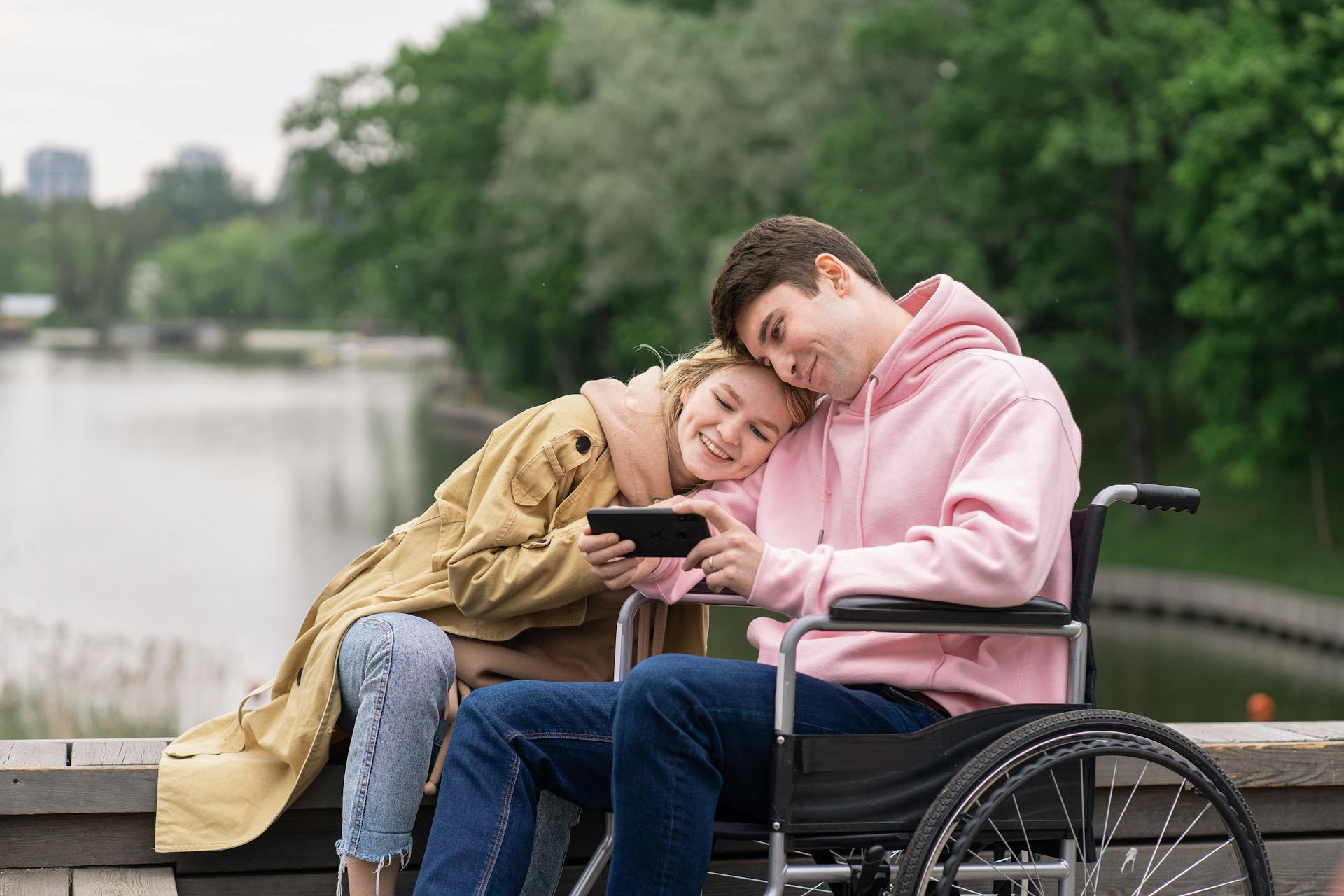 A man in a wheelchair looking at a smartphone beside his wife | Source: Pexels