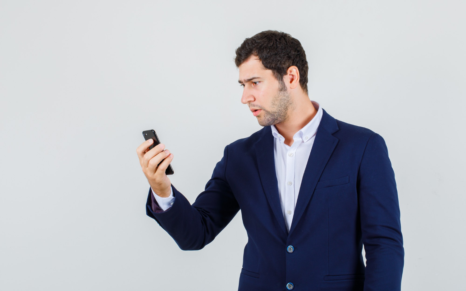 A startled young man looking at a phone | Source: Freepik