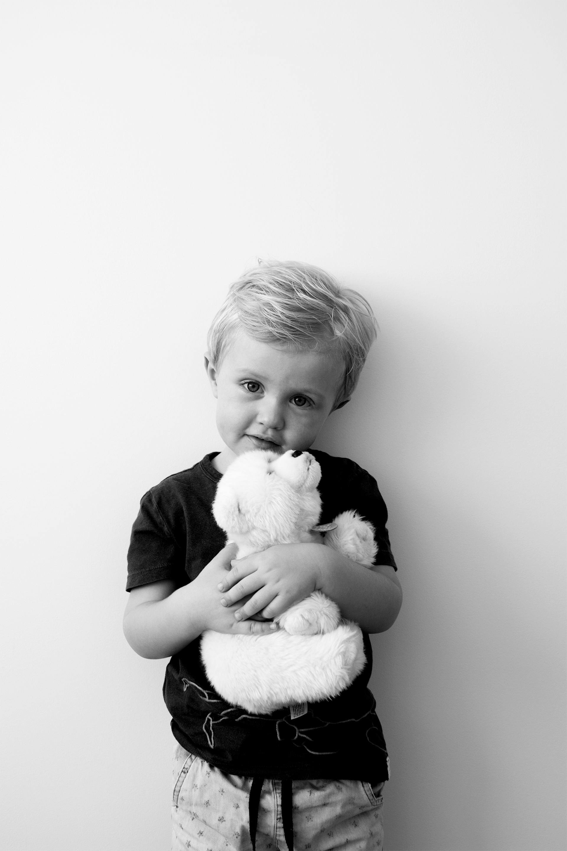 A grayscale photo of a boy holding a stuffed bear | Source: Pexels