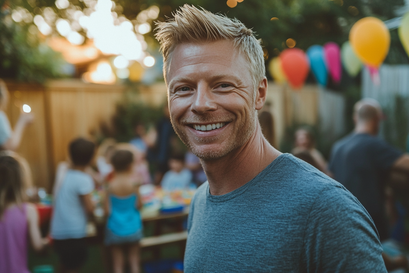 Man smiling at a backyard birthday party | Source: Midjourney