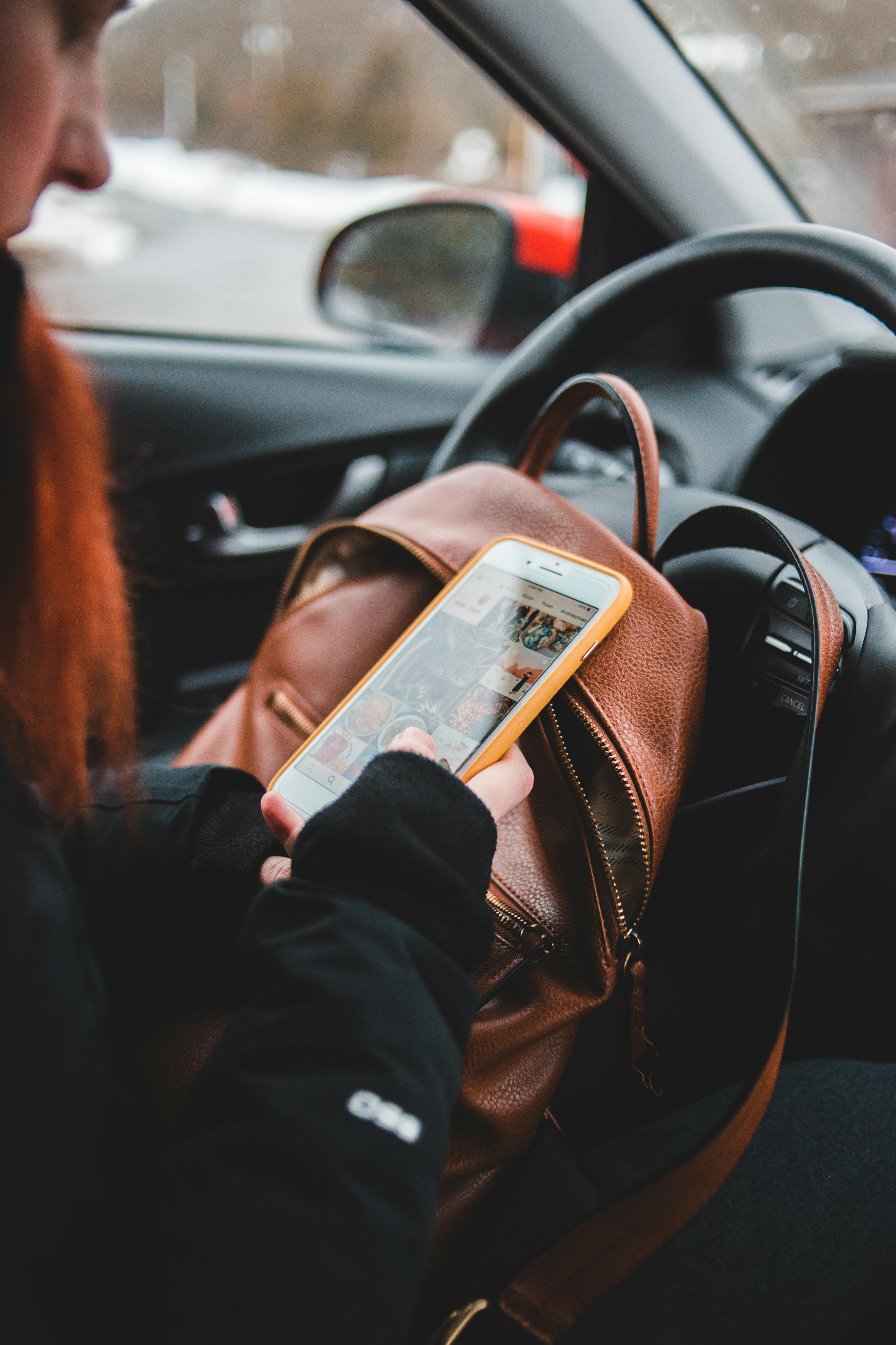 A woman checking her phone from inside the car | Source: Pexels