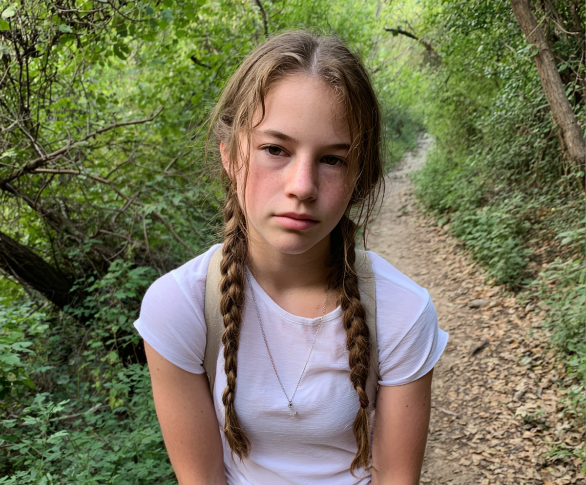A stressed teenage girl wearing a white t-shirt on a hike | Source: Midjourney