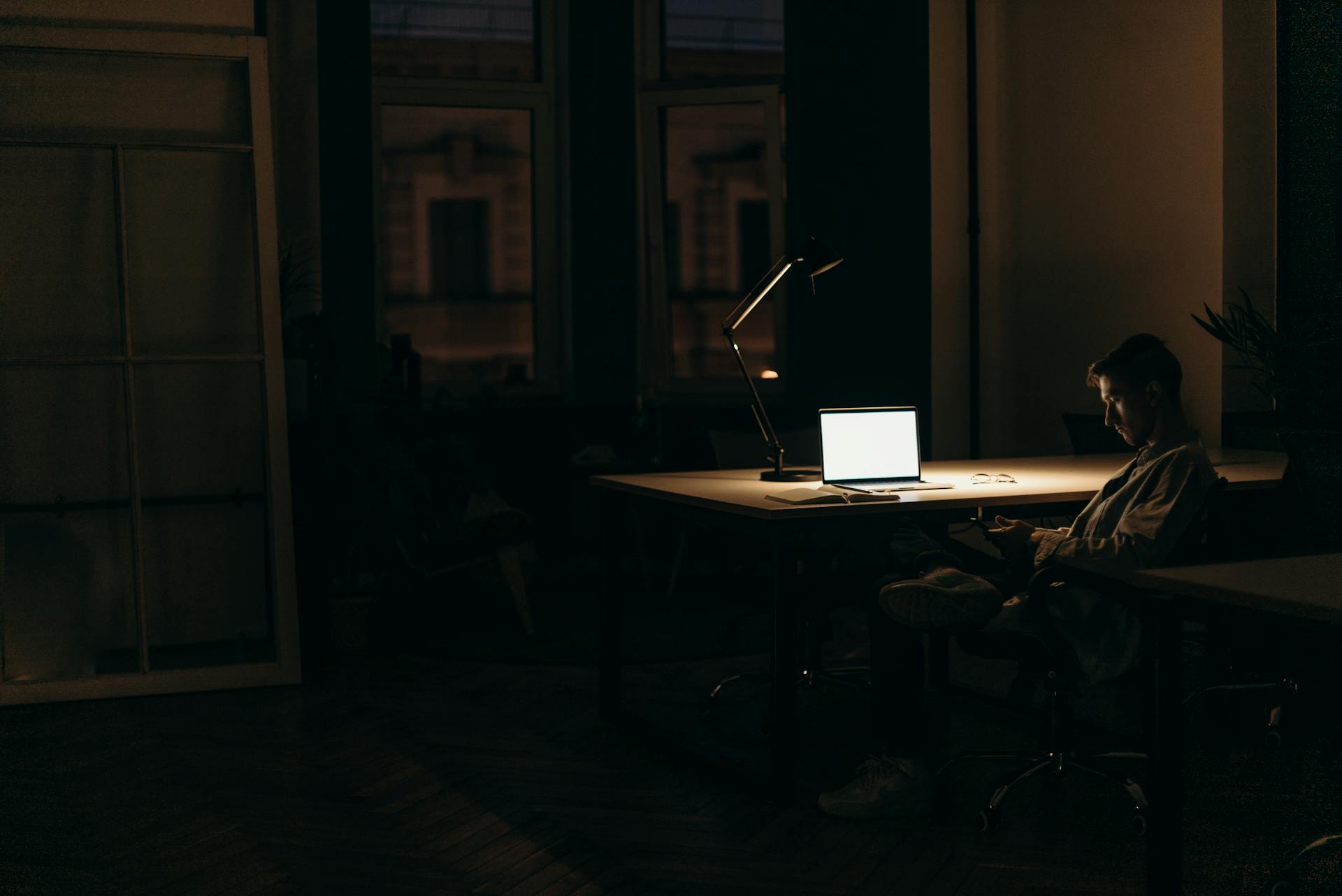 A man seated at a desk in a dark room | Source: Pexels