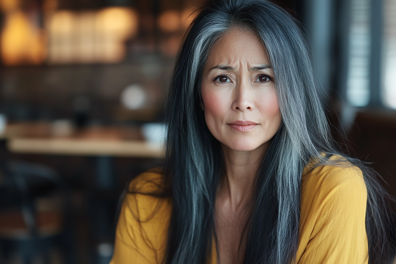 A woman in a café, her expression sad and worried | Source: Midjourney