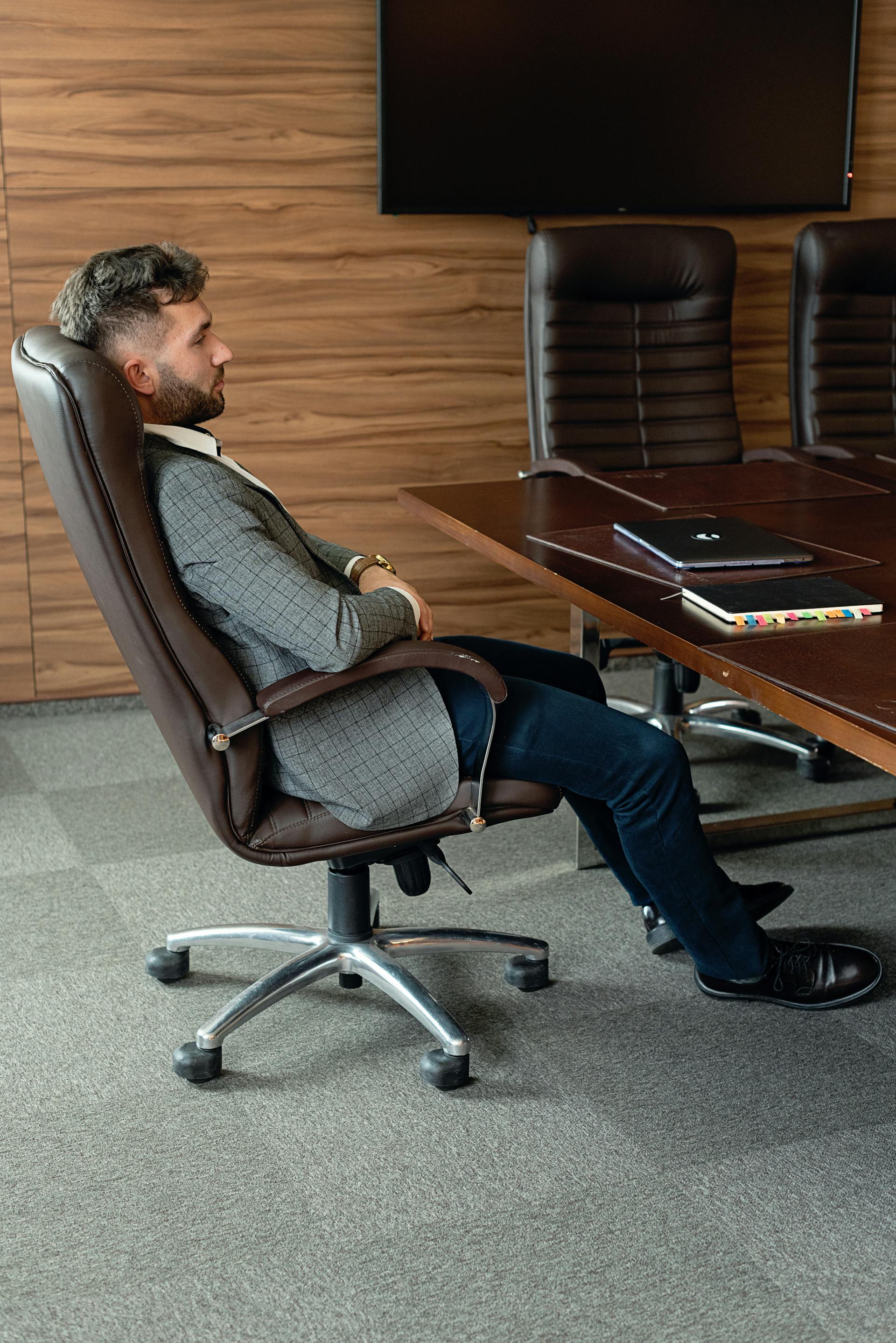A side-view of a man leaning back in his office chair | Source: Pexels