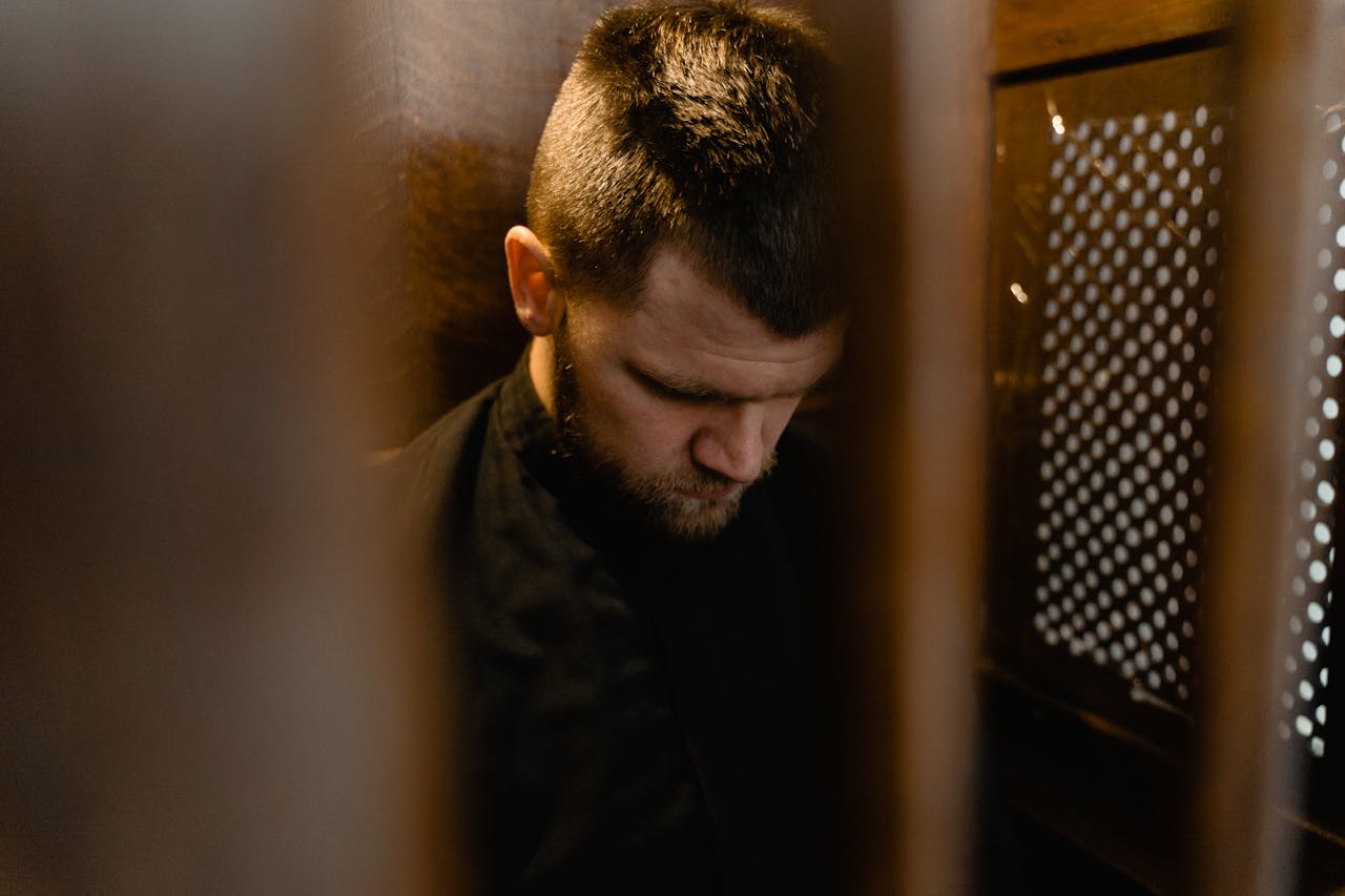 A man in a confession booth in church | Source: Pexels