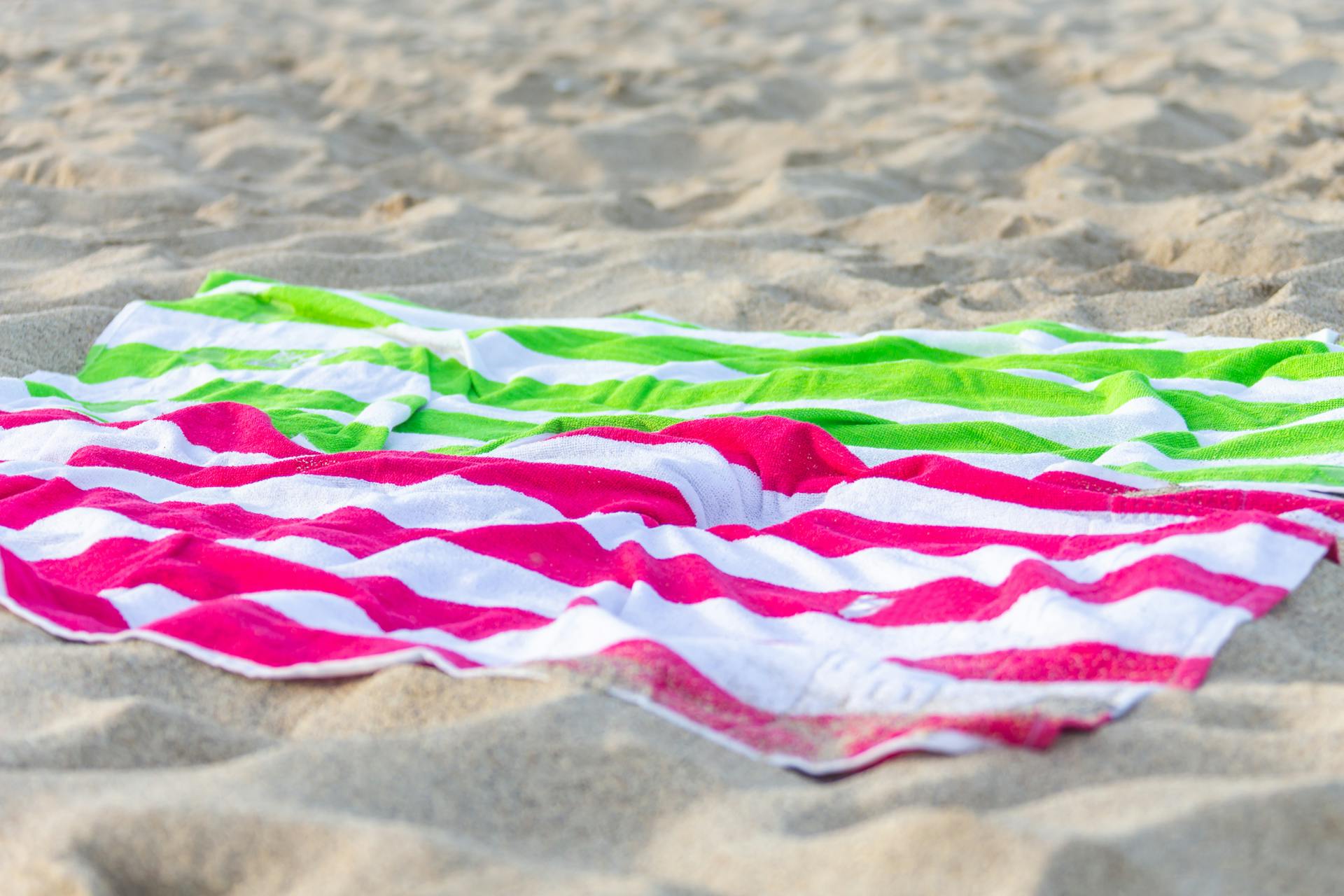 Bright pink and green striped towels on the sand | Source: Pexels
