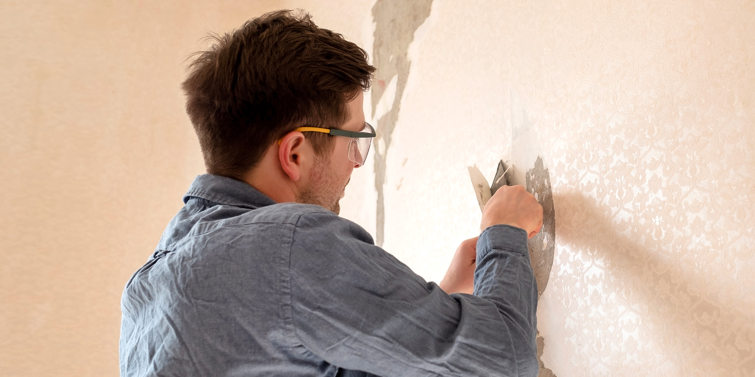 A man peeling off wallpaper | Source: Shutterstock