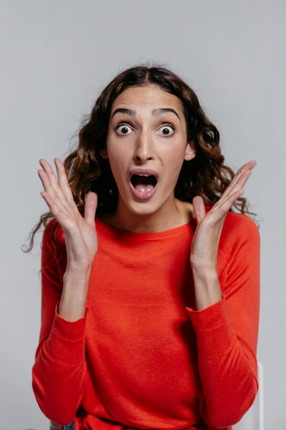 A shocked woman in a red sweater | Source: Pexels