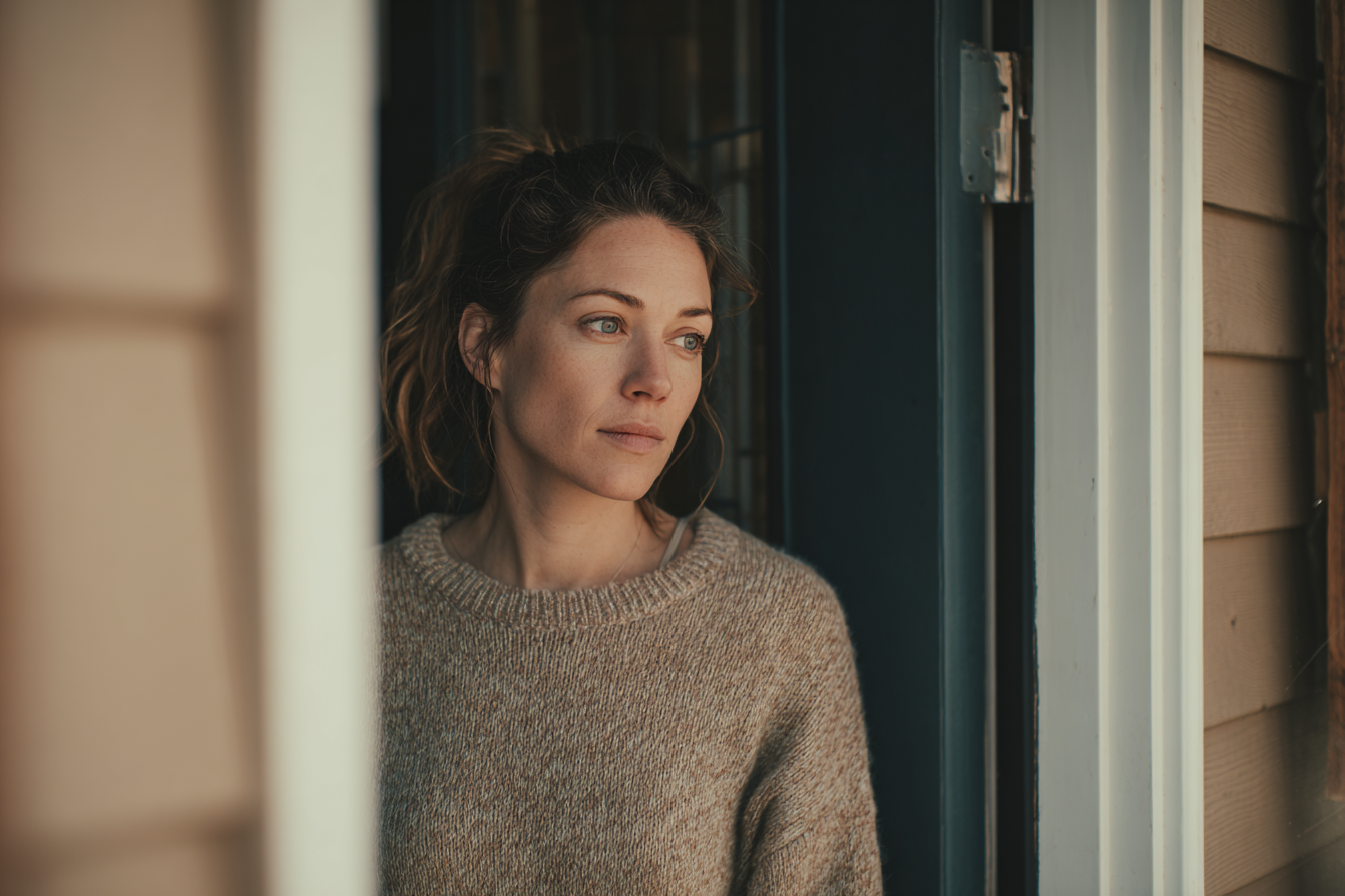 A woman standing in the doorway of her house | Source: Midjourney