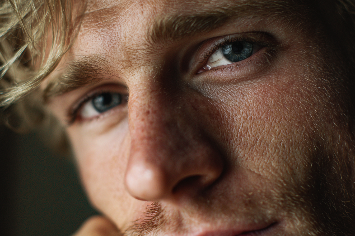A man with an emotional look in his eyes smiling faintly at someone | Source: Midjourney