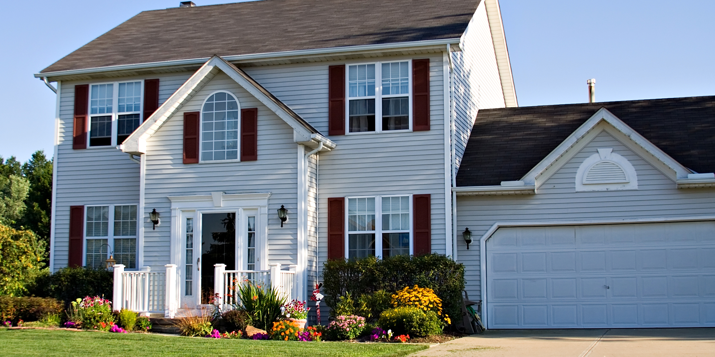 A suburban home with white siding and red shutters | Source: Shutterstock