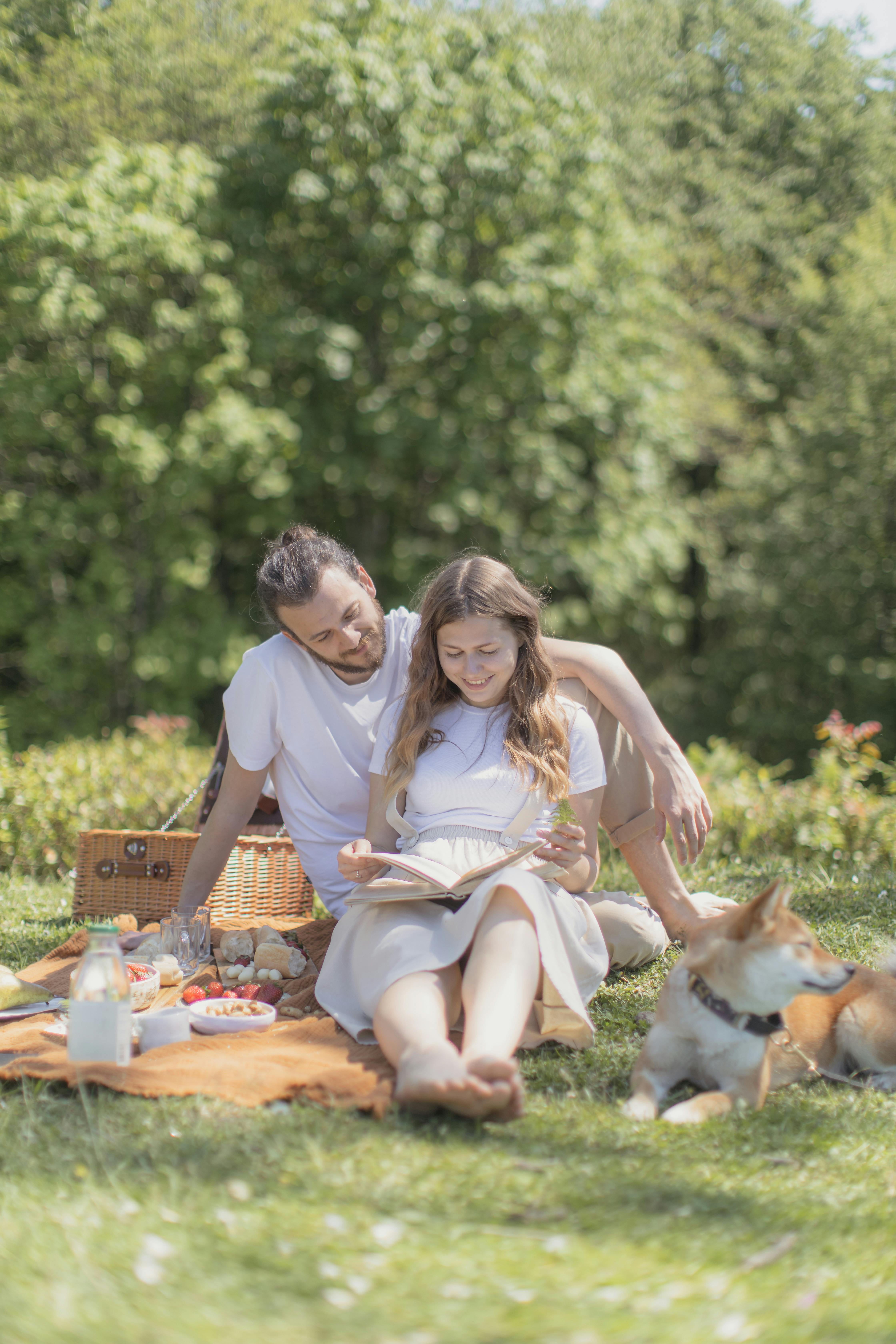 Couple assis sur un tapis de pique-nique avec un chien | Source : Pexels