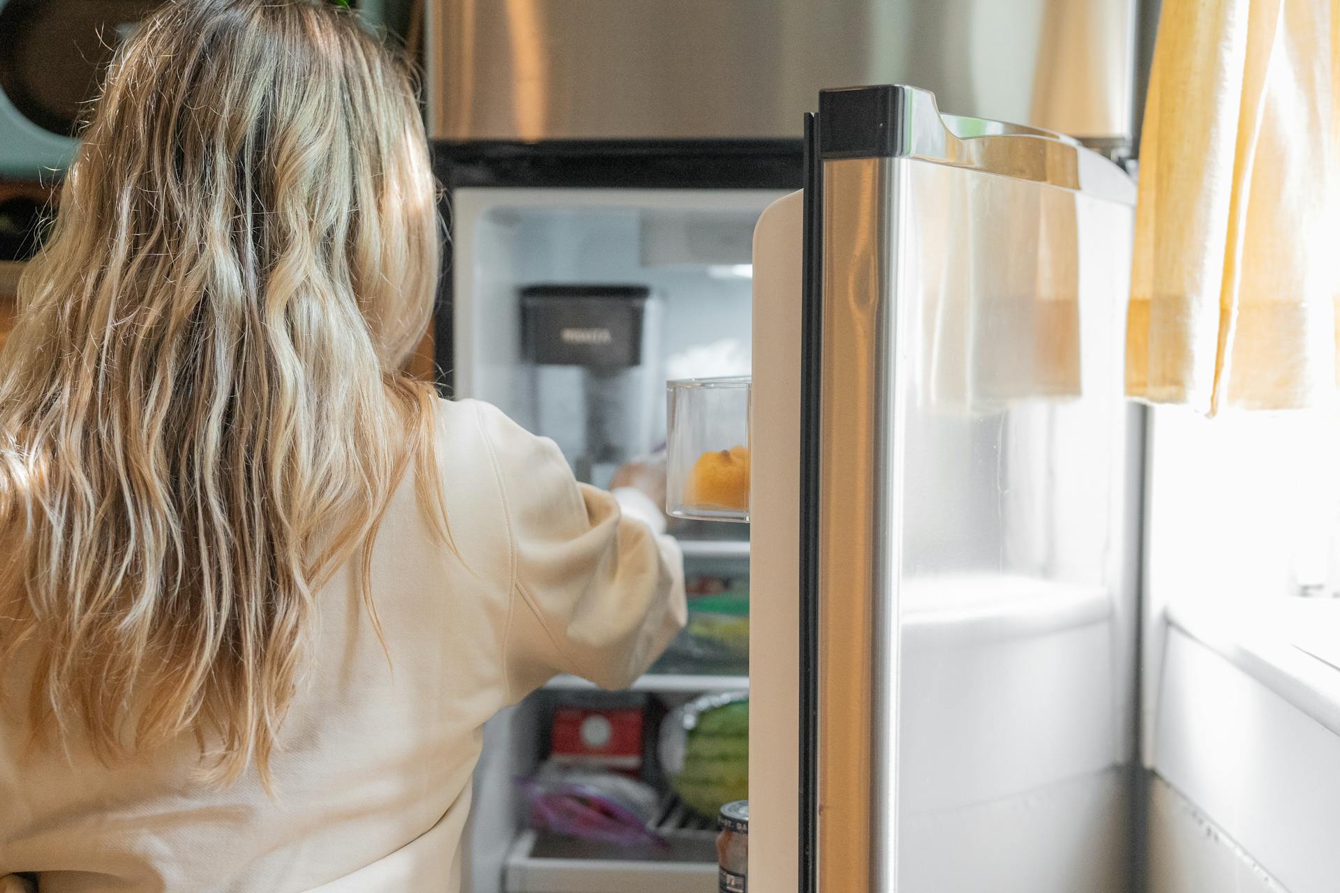 A woman reaching into a fridge | Source: Pexels