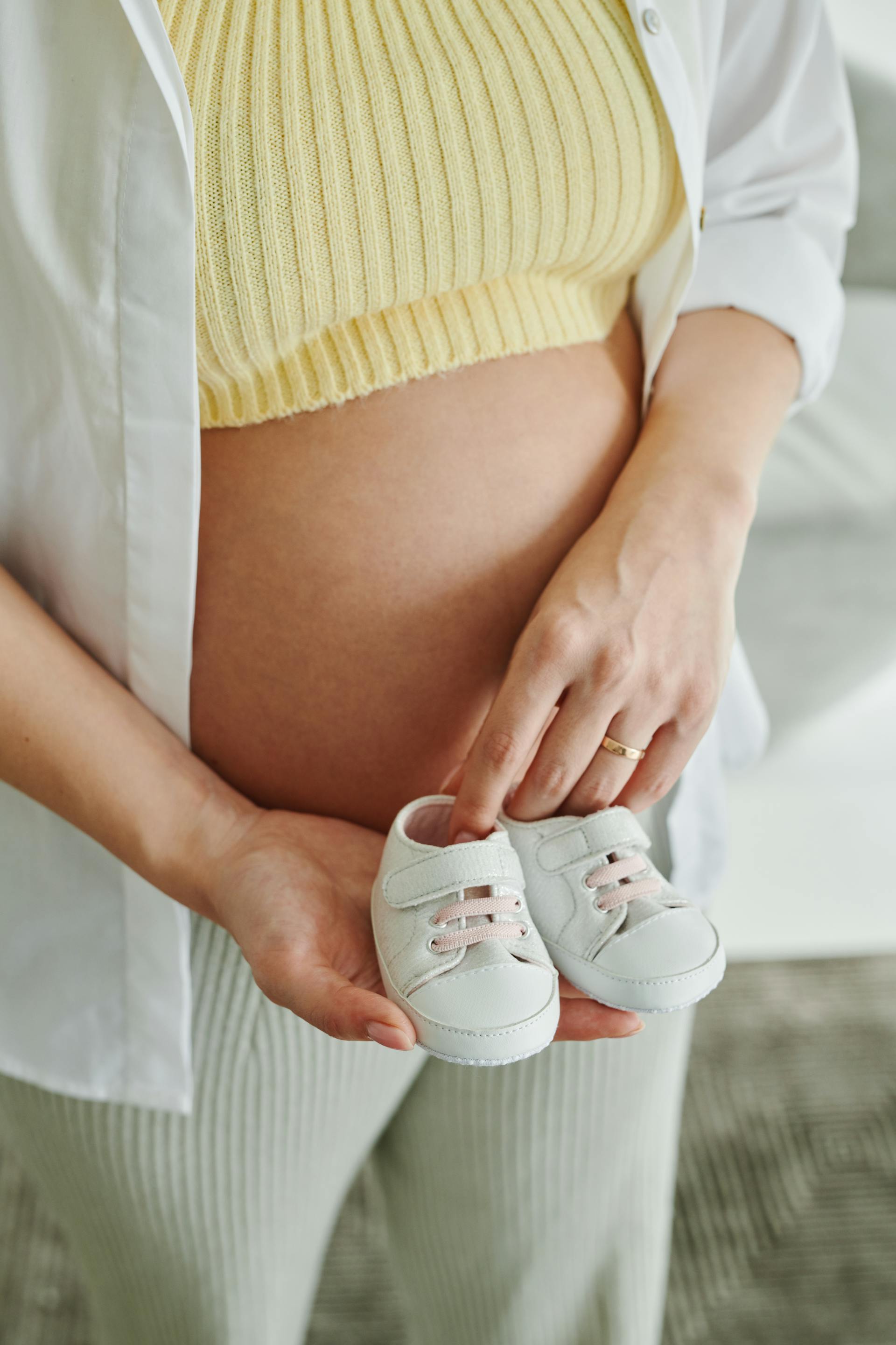 A pregnant woman holding baby shoes | Source: Pexels