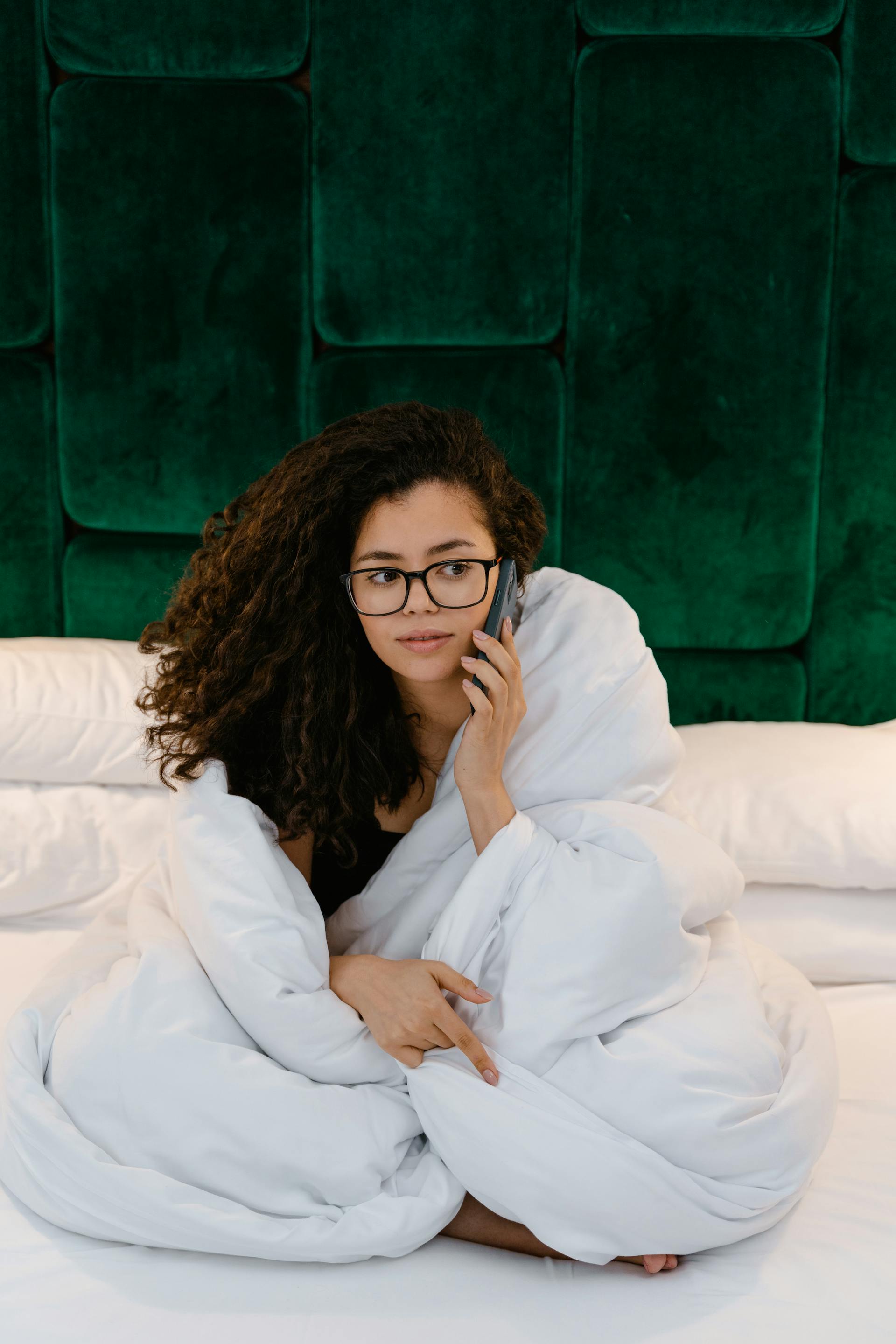 A woman in bed answering a phone call | Source: Pexels