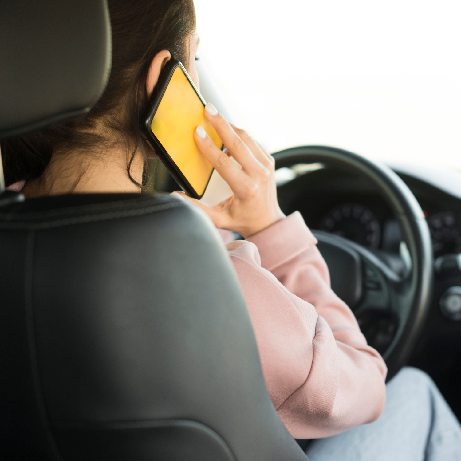 A woman talking on the phone while seated behind the wheel | Source: Freepik