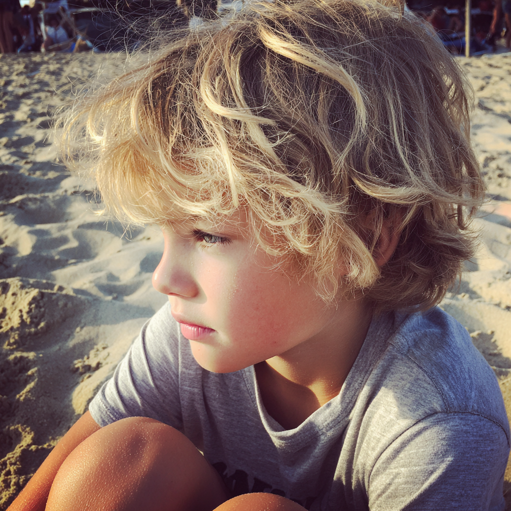 A little boy sitting at the beach | Source: Midjourney