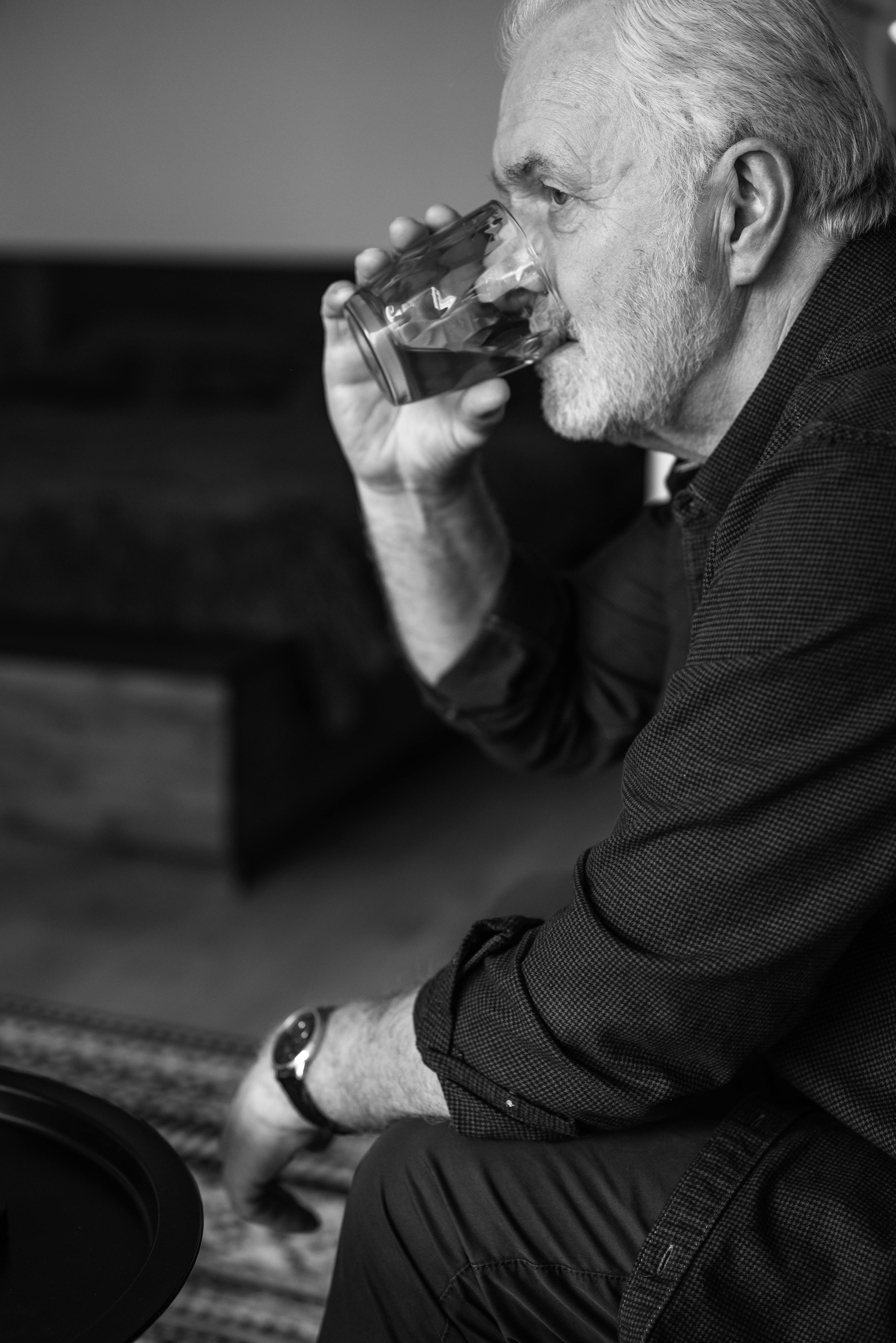 Man sitting on a couch drinking water | Source: Pexels