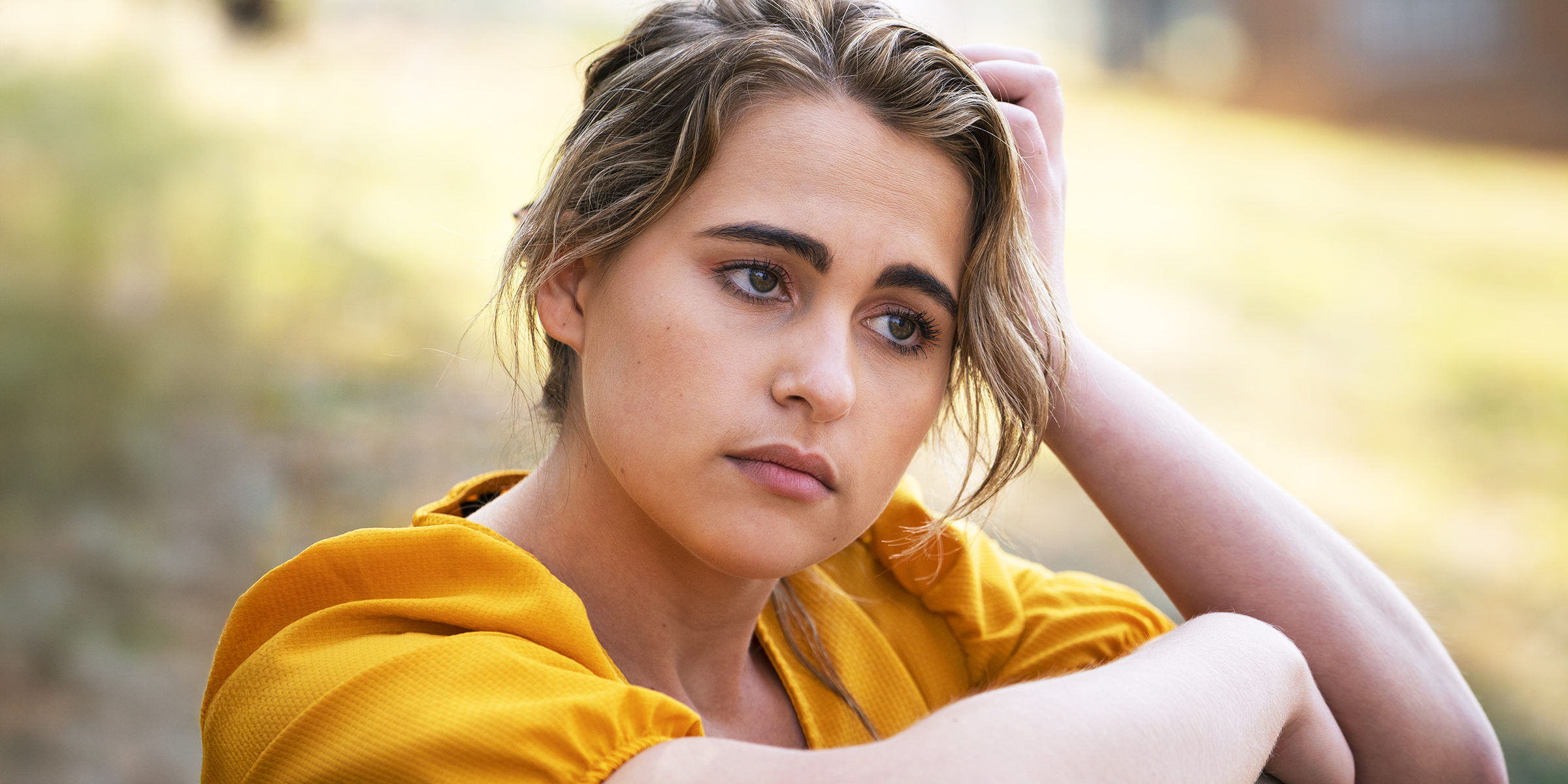 A young woman in a yellow dress lost in thought | Source: Freepik