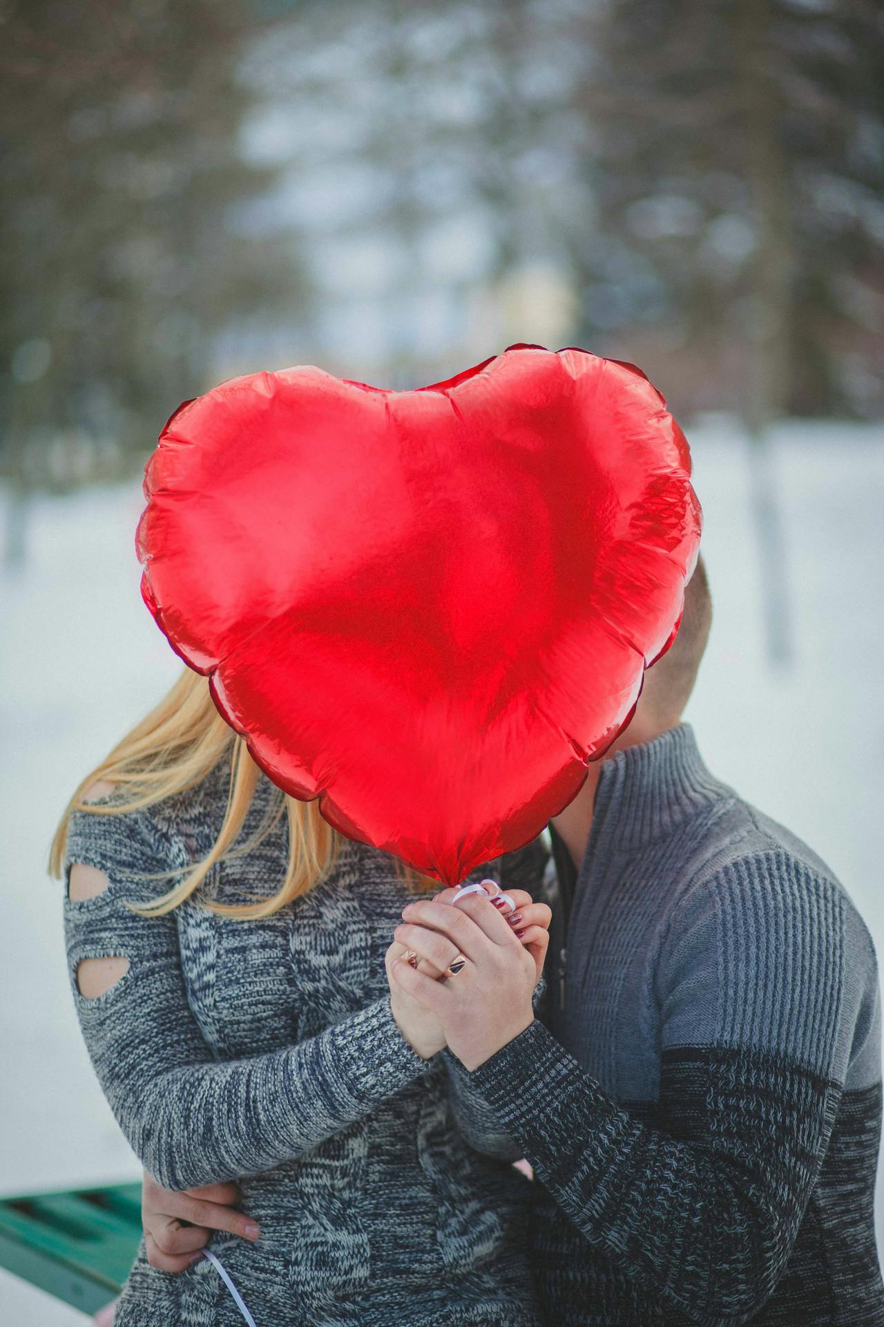 A romantic couple holding a red heart-shaped balloon | Source: Pexels