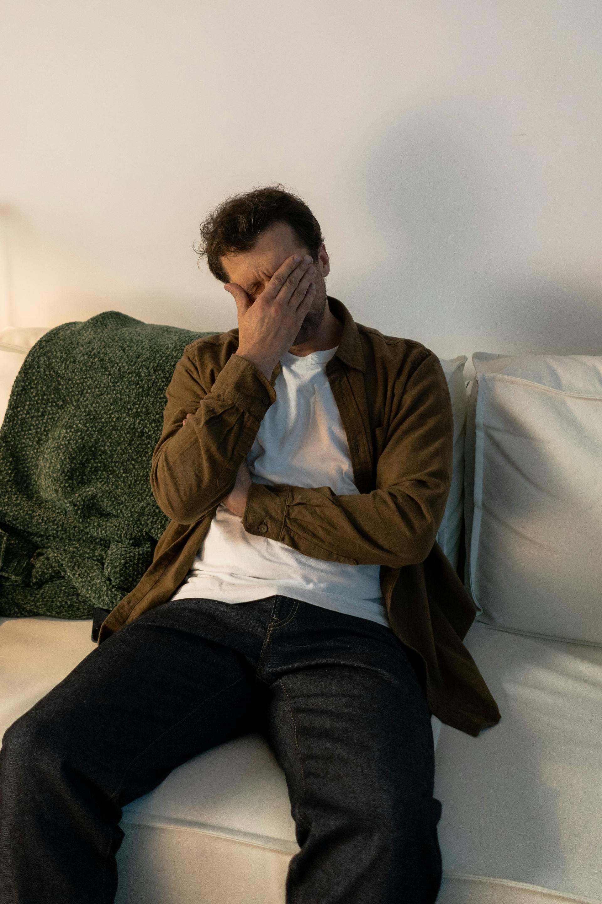 A depressed man hiding his face with his hand | Source: Pexels