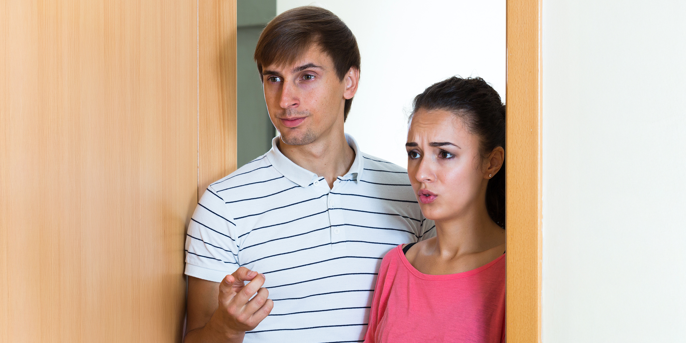 An anxious couple standing at a doorway | Source: Shutterstock