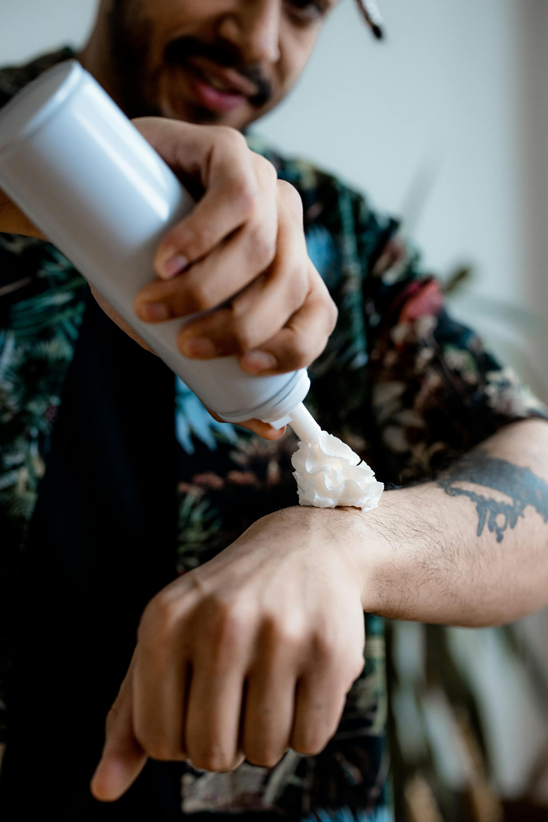 A man spraying whipped cream on his arm | Source: Pexels
