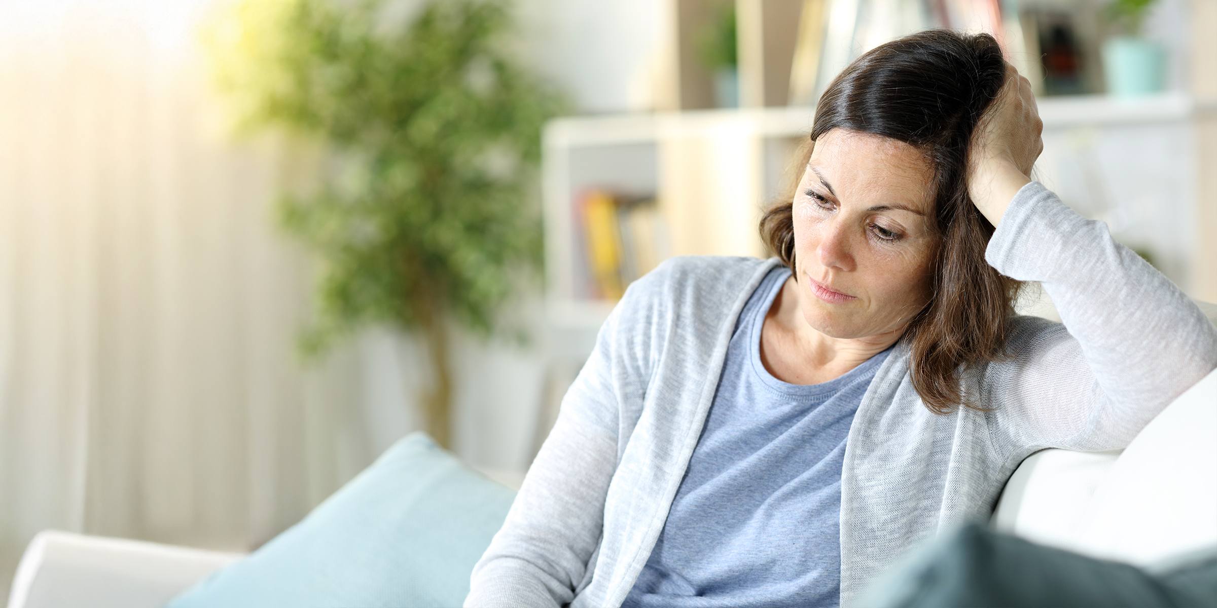 A sad and thoughtful woman in a living room | Source: Shutterstock