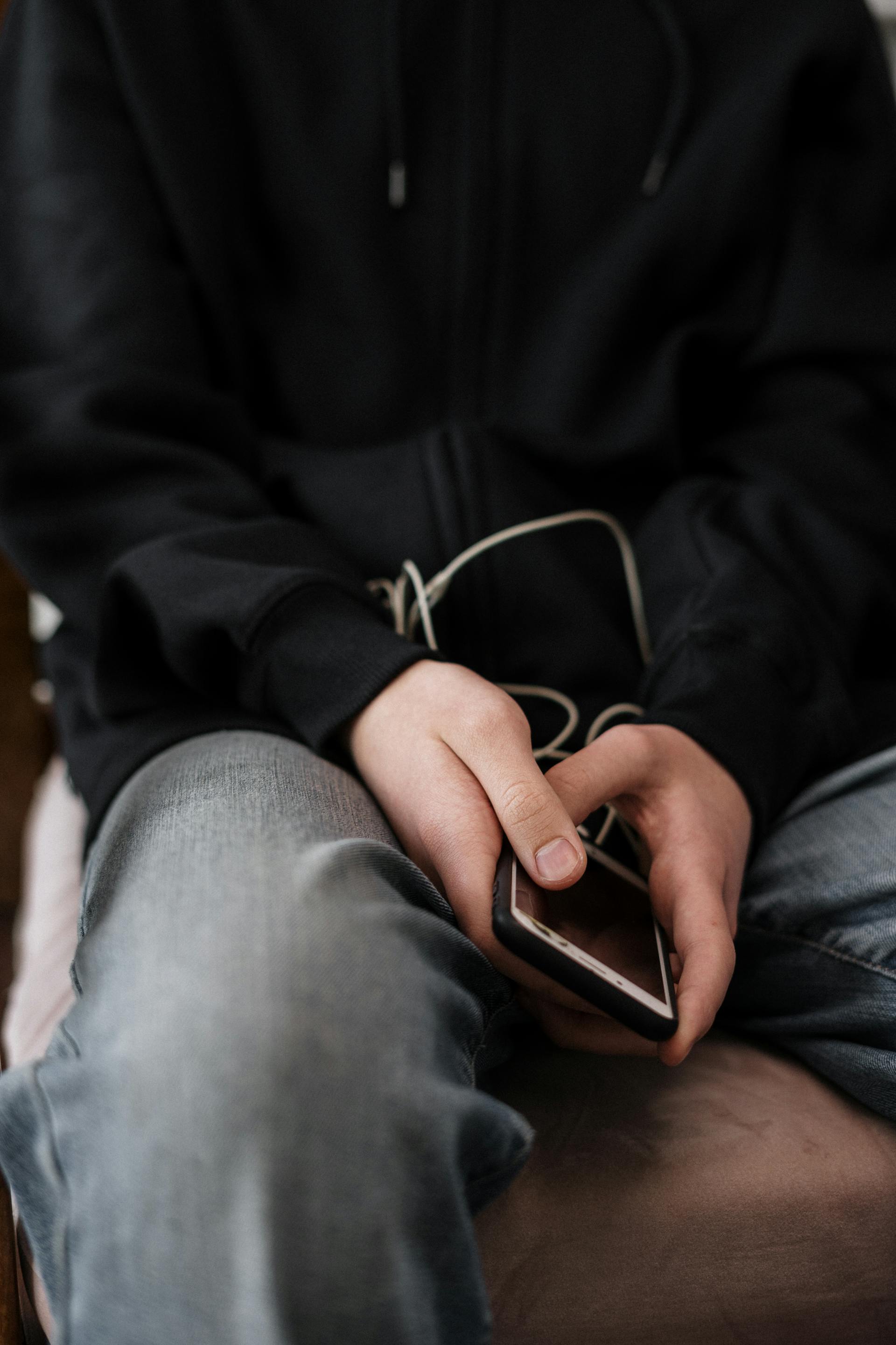 A close-up shot of a person in a jacket and denim jeans holding a phone | Source: Pexels