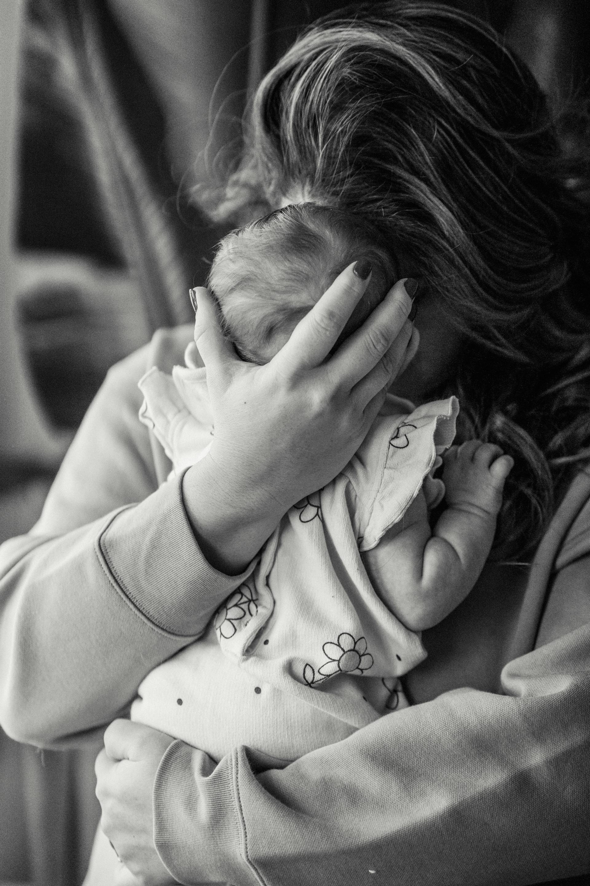 A grayscale photo of a woman hugging her baby | Source: Pexels
