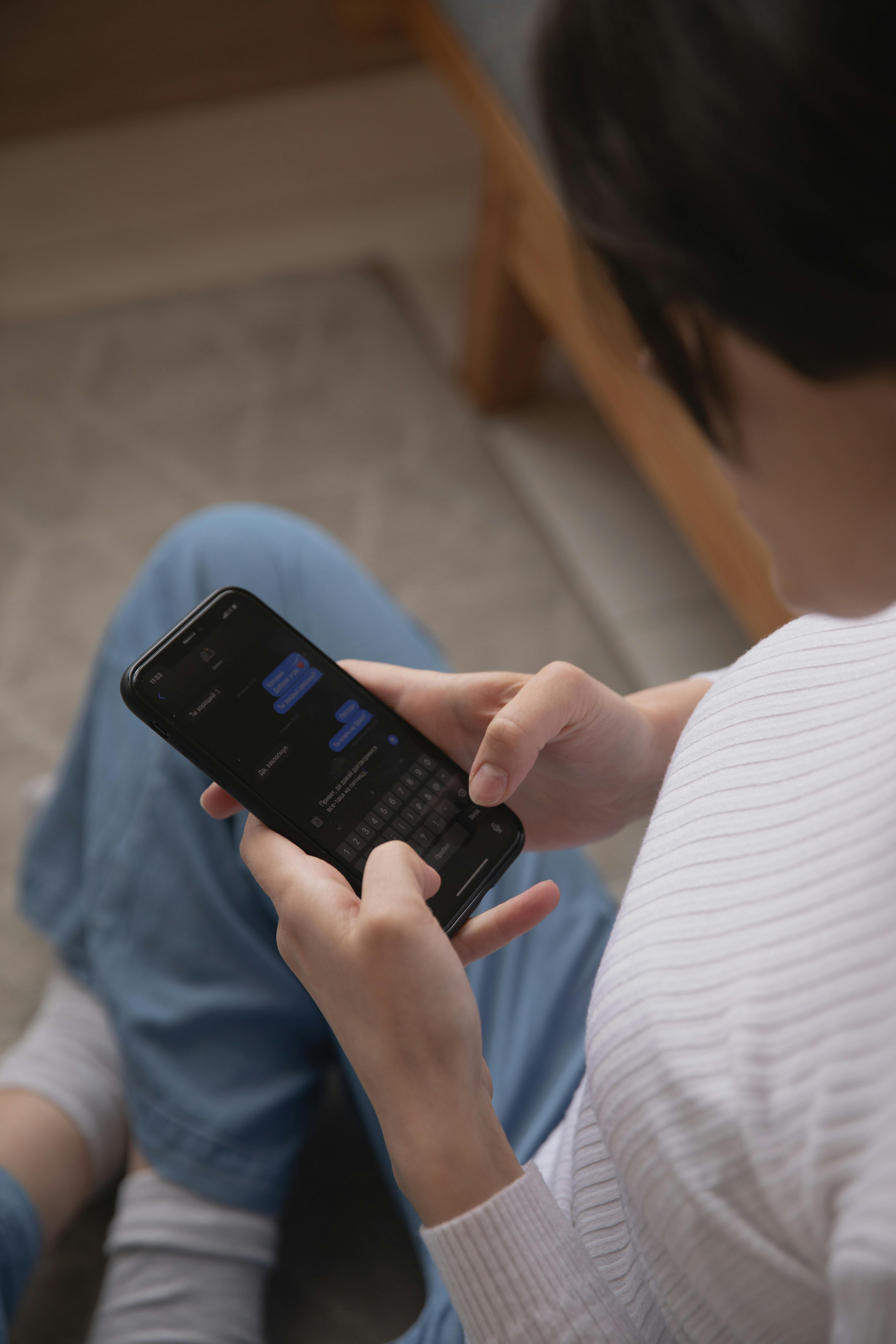 A woman sitting on the floor using her phone | Source: Pexels