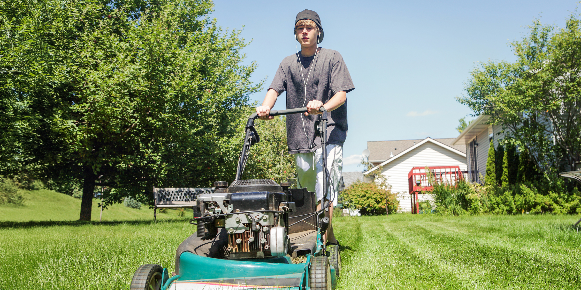 A teenage boy mowing a lawn on a sunny afternoon | Source: Shutterstock